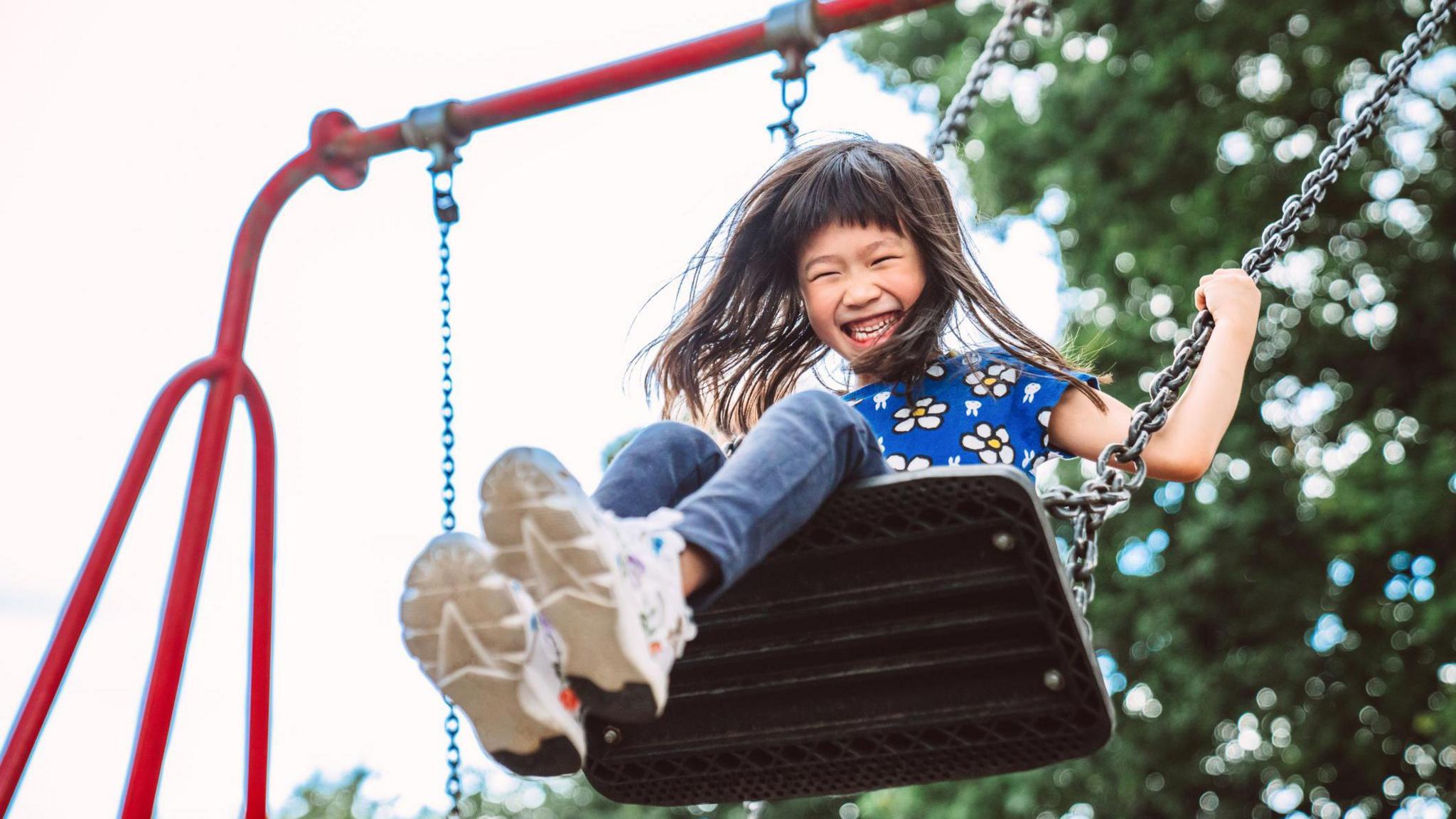 girl on swing smiling at play park