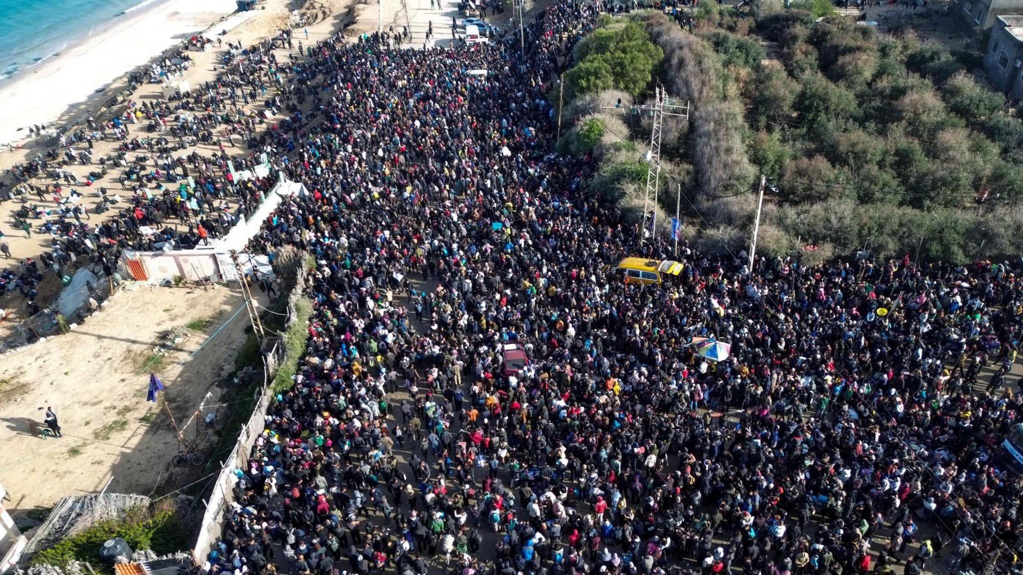 Drone shows Palestinians waiting to return to the northern Gaza Strip from the southern Gaza Strip, along Rashid Road, west of the Nuseirat refugee camp on 26 January 