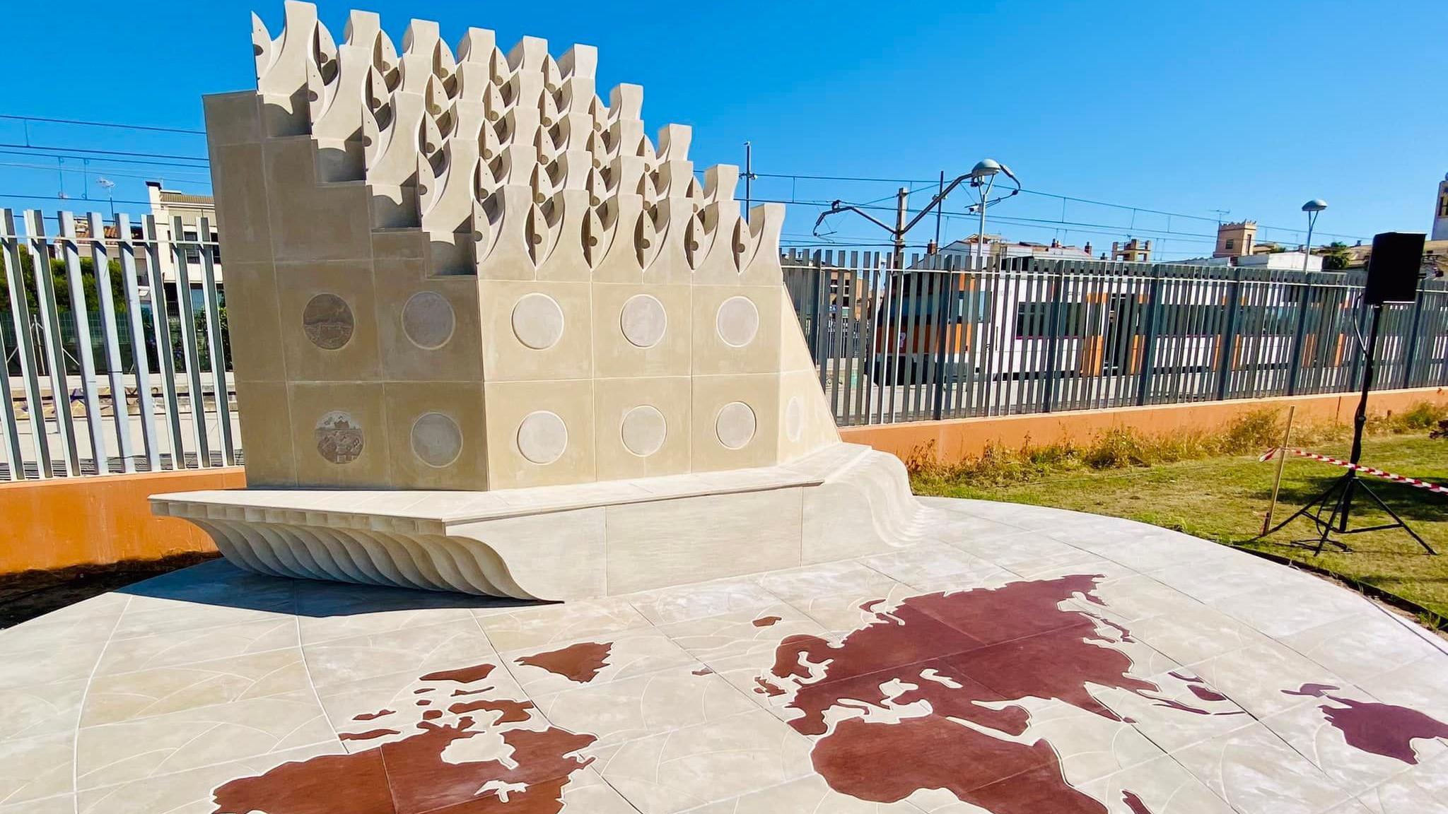 The "living monument" at Solidarity Park in Malgrat de Mar. It is a white stone sculpture resembling a ship. Its base consists of stone blocks depicting a world map.