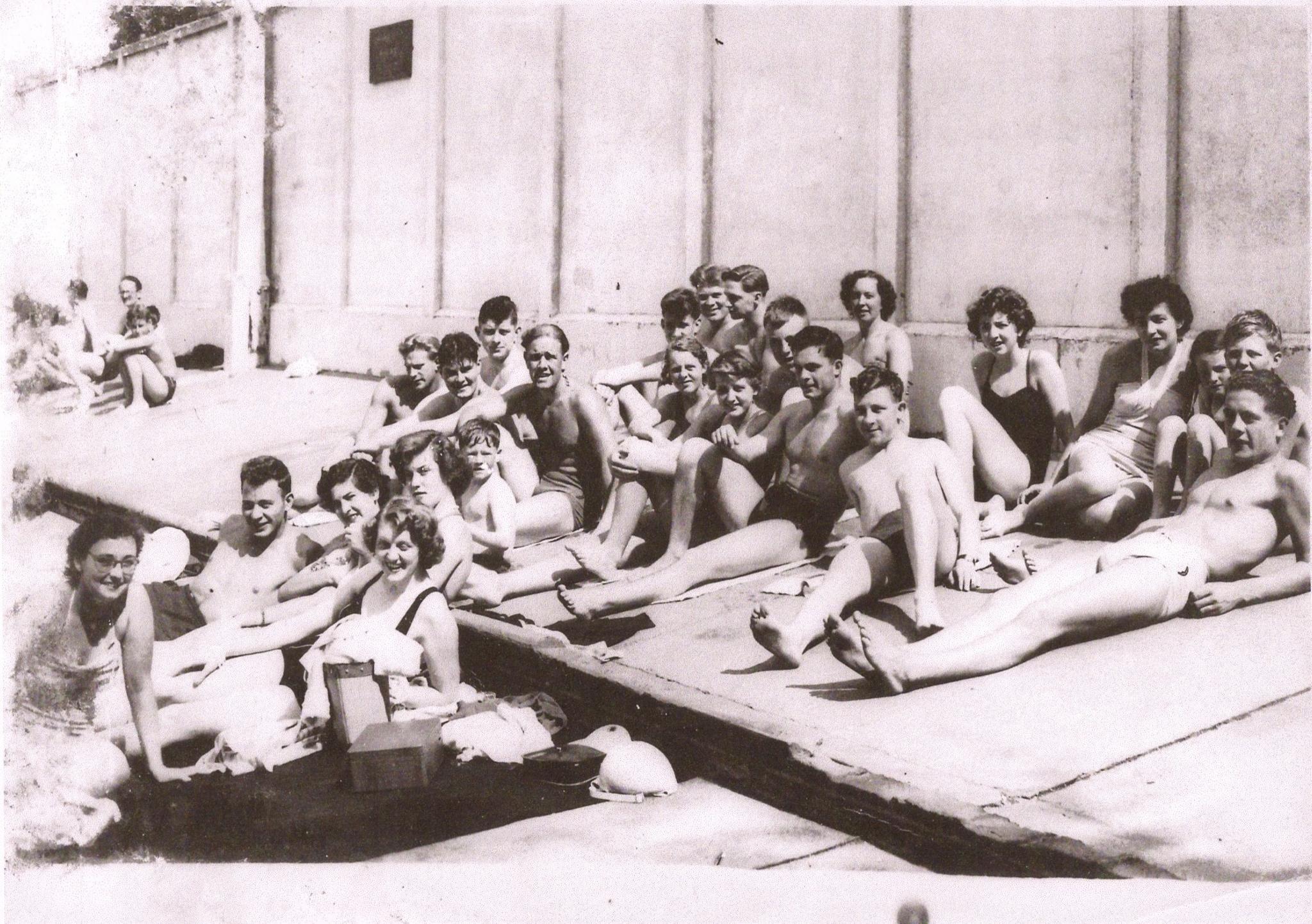 A black and white photo of people sitting or lying on the hard surface at Broomhill Pool