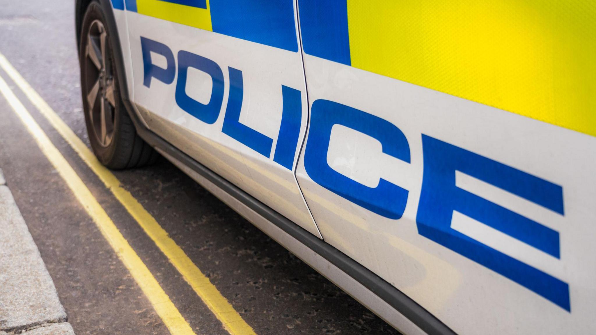 A close up of a police car parked on a double yellow line. 