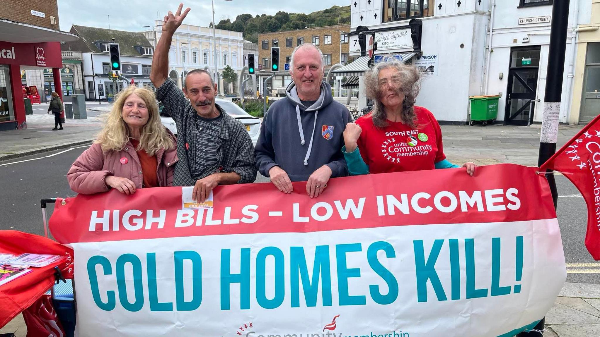 Four protestors in Dover Town Square holding a banner saying High Bills, Low Incomes, Cold Homes Kill.