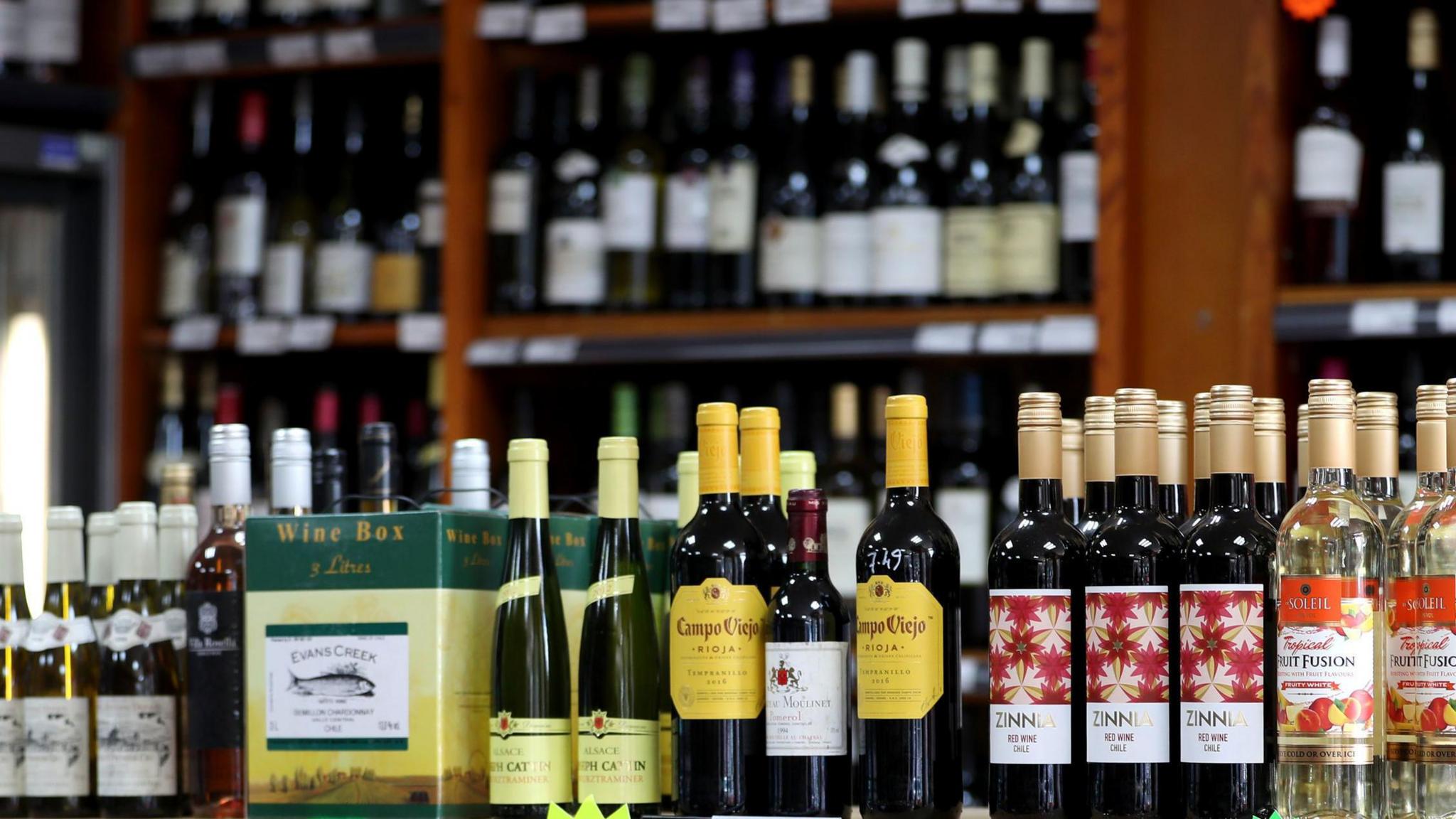 Photo shows the inside of an off-licence with rows of shelves with bottles of alcohol on them