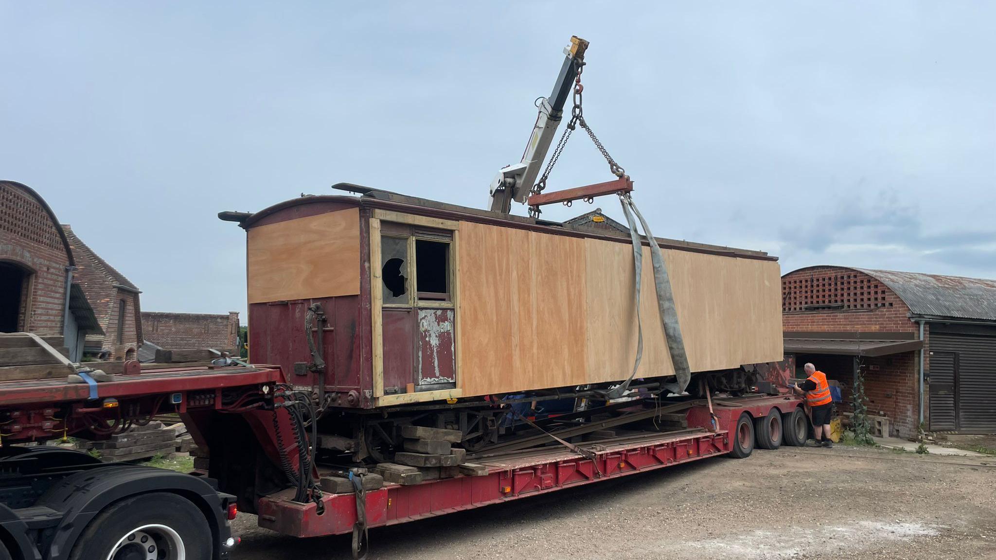 The boarded up carriage is lowered on to a long truck.