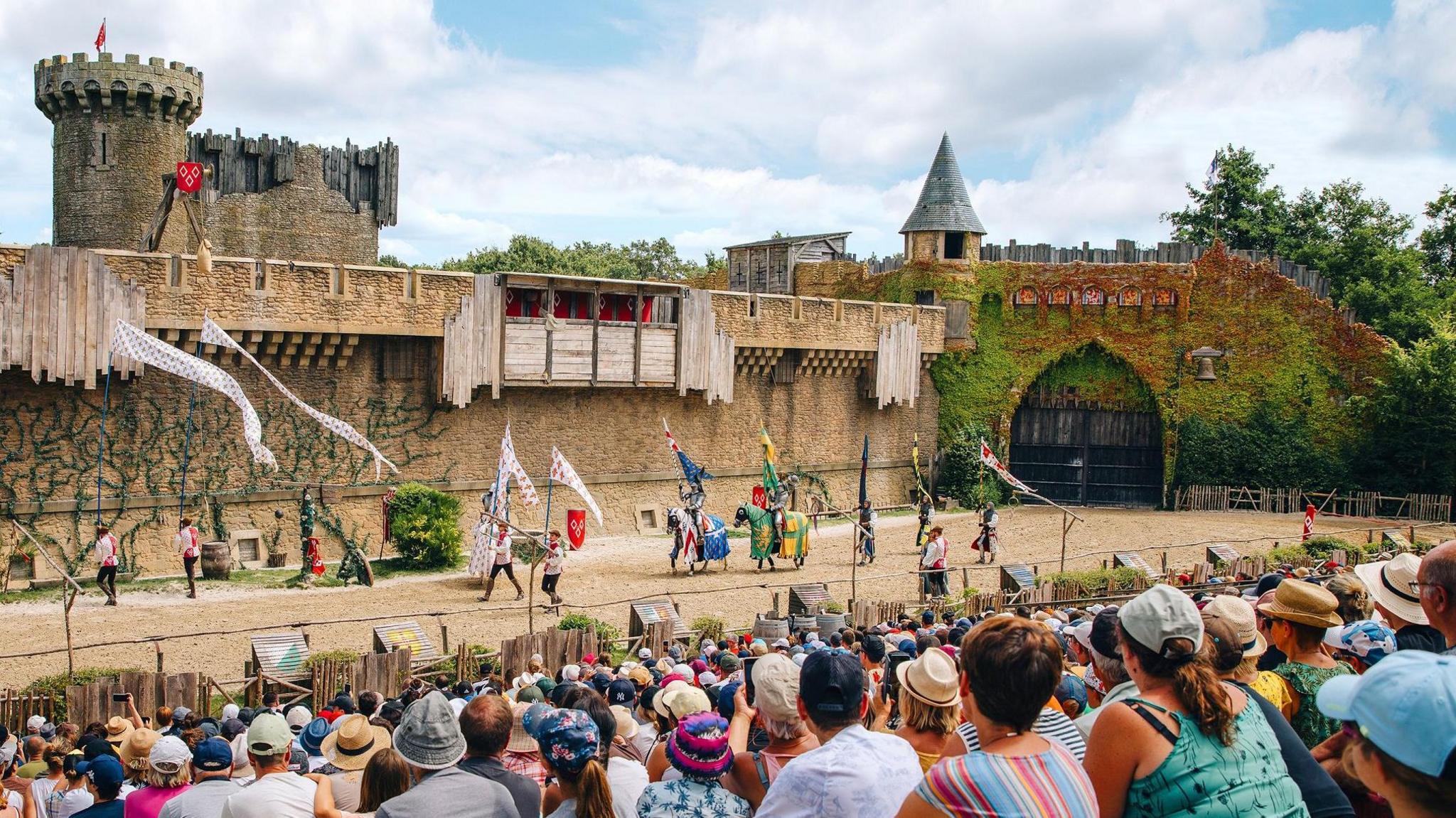 A re-enactment at one of the Puy du Fou exhibits, with actors on horseback walking in front of a seated crowd  