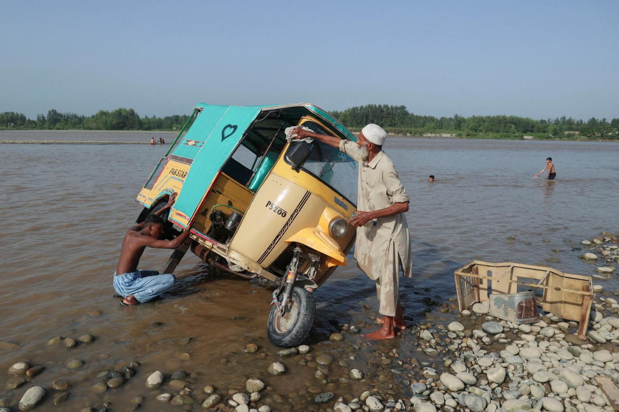 Men wash a rickshaw at the shore of Kabul river, 