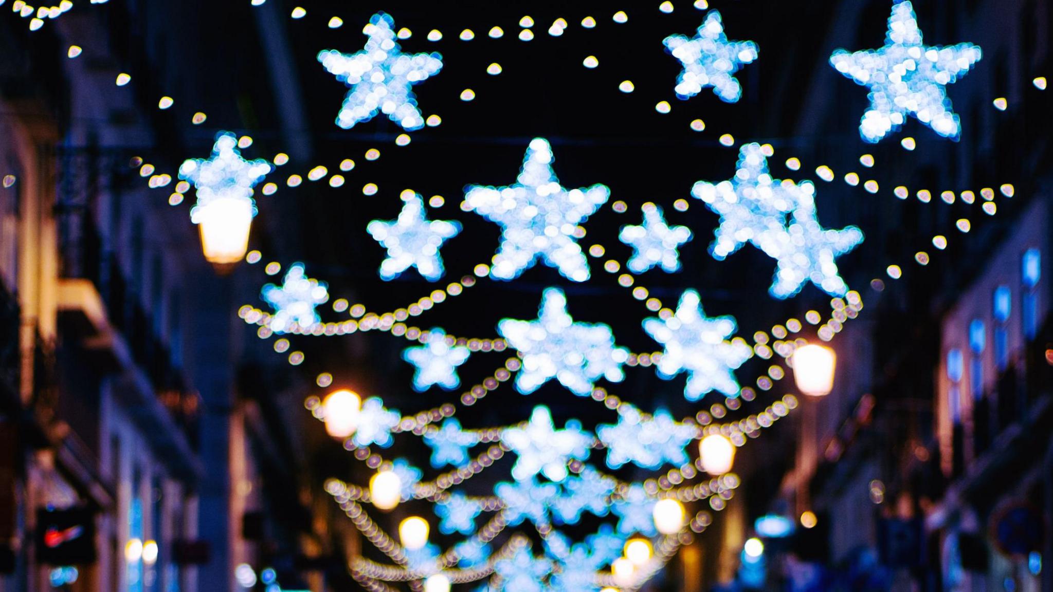 Street at night with out of focus Christmas lights in star patterns