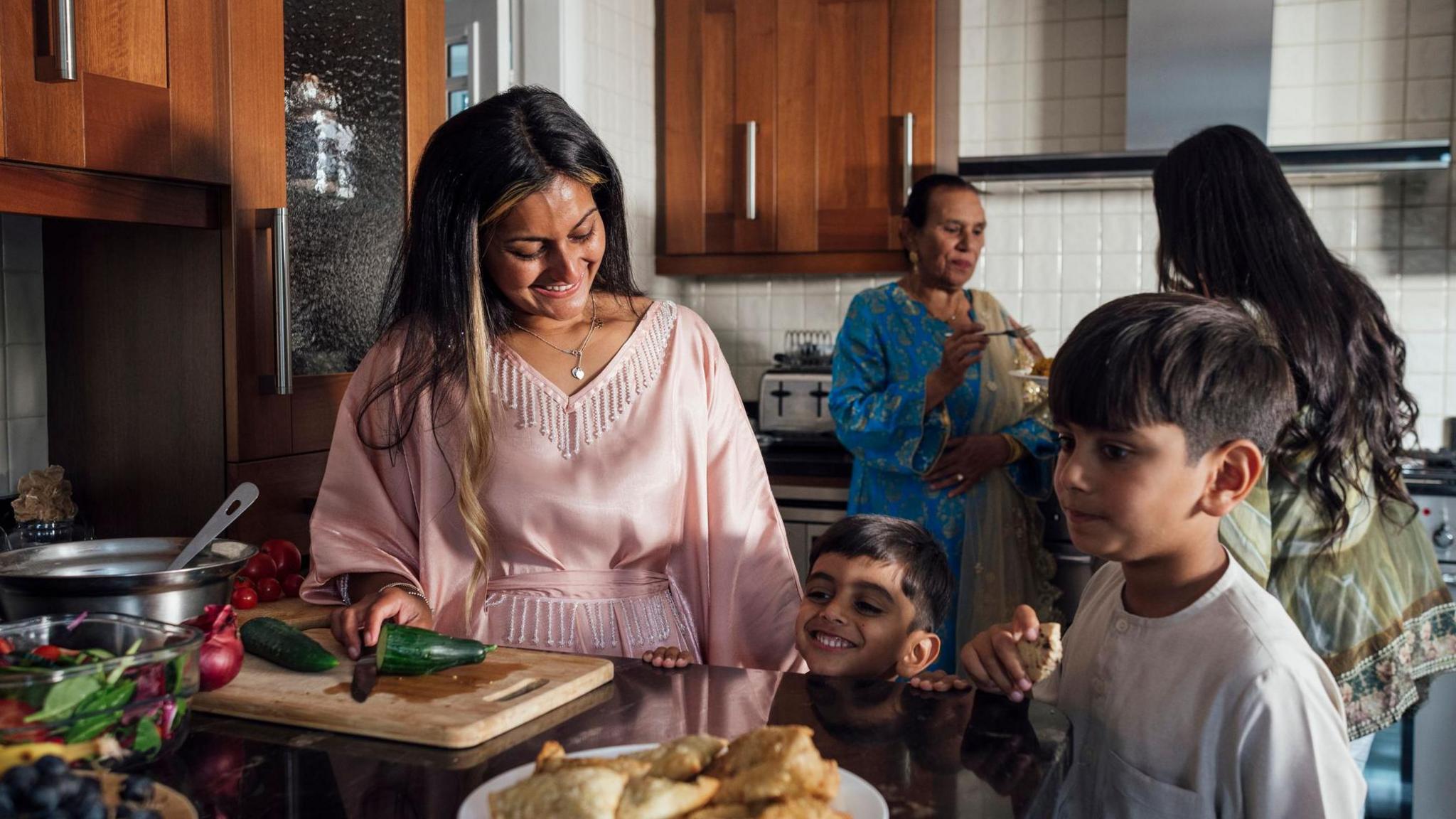 A multi-generational family gathered for Eid celebrations at home in Middlesbrough, North East England. They are all dressed in traditional outfits for the occasion. 