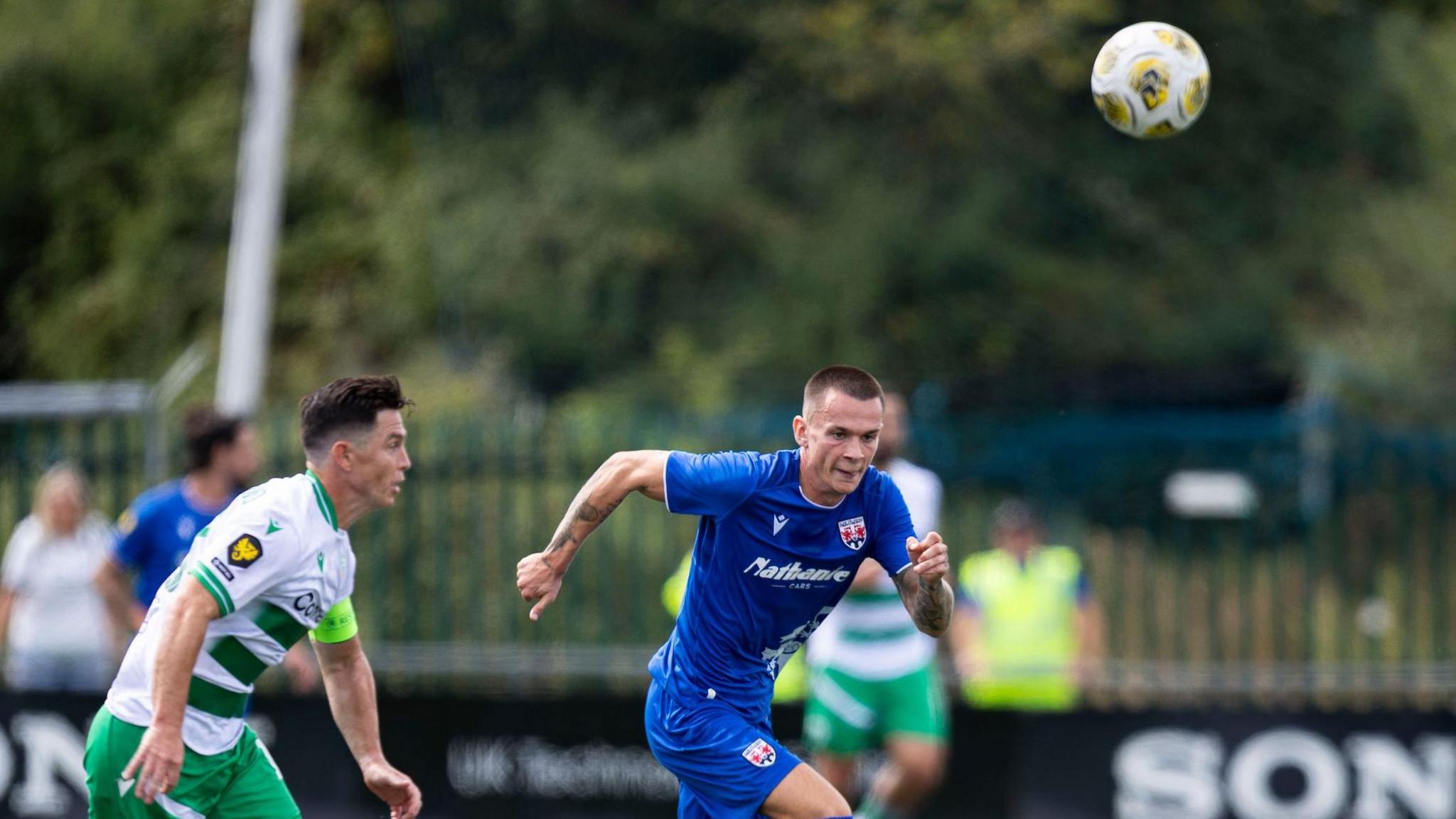 Penybont's Ryan Hill chases after the ball with TNS captain Danny Redmond in pursuit