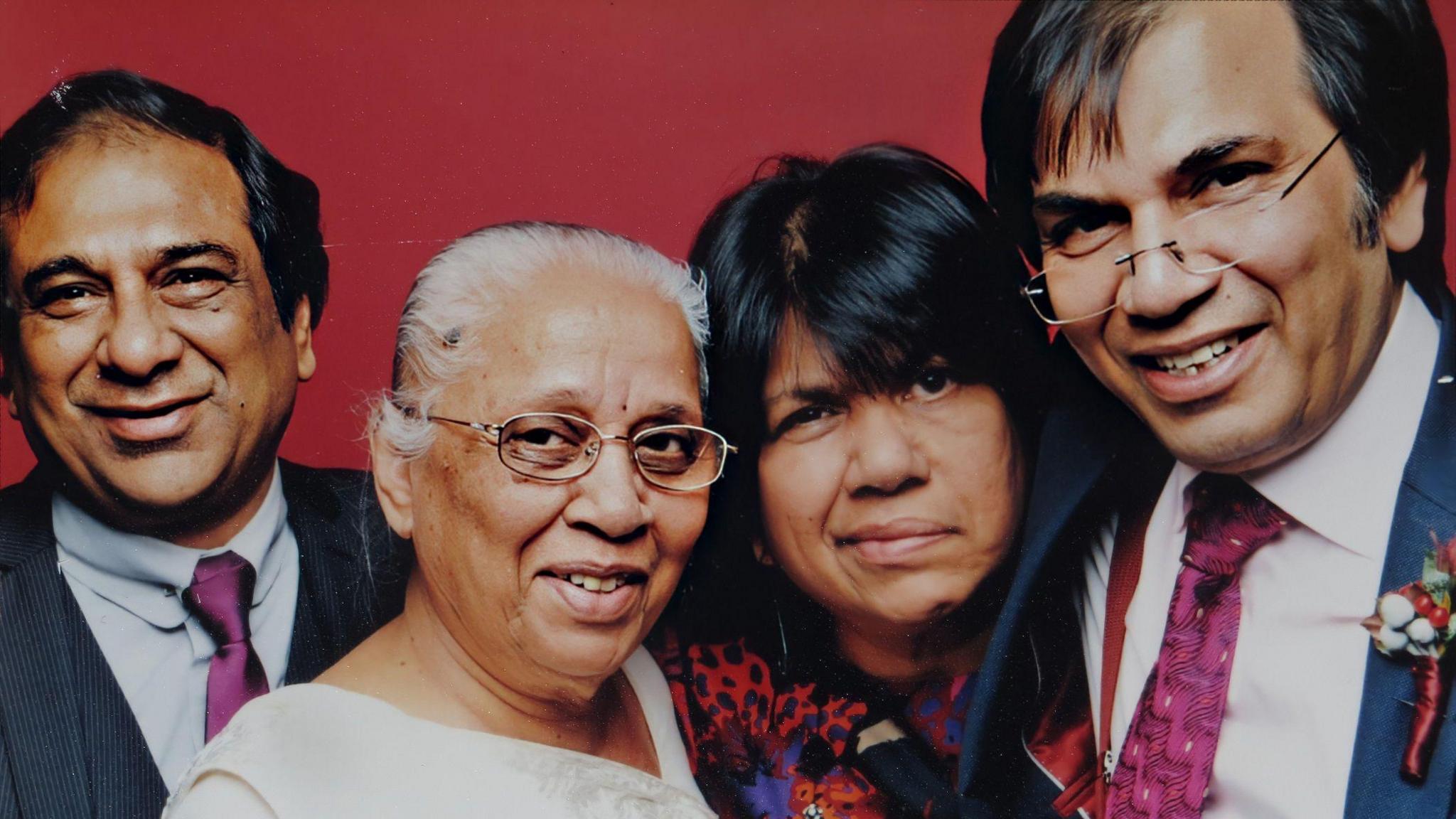 A full-colour portrait of Tara Mistry's family. On the left is a man wearing a suit and tie. To the right is an older woman with white hair and glasses. To the right is Tara Mistry and on the far right is a man wearing a suit and glasses.