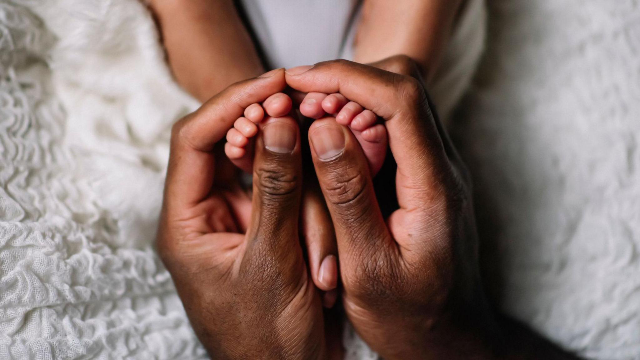 A close-up of a father hand holding a baby feet