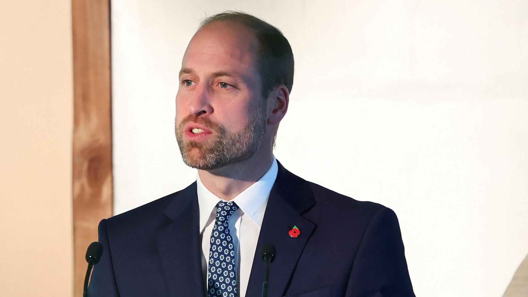 Prince William speaking at a podium. 