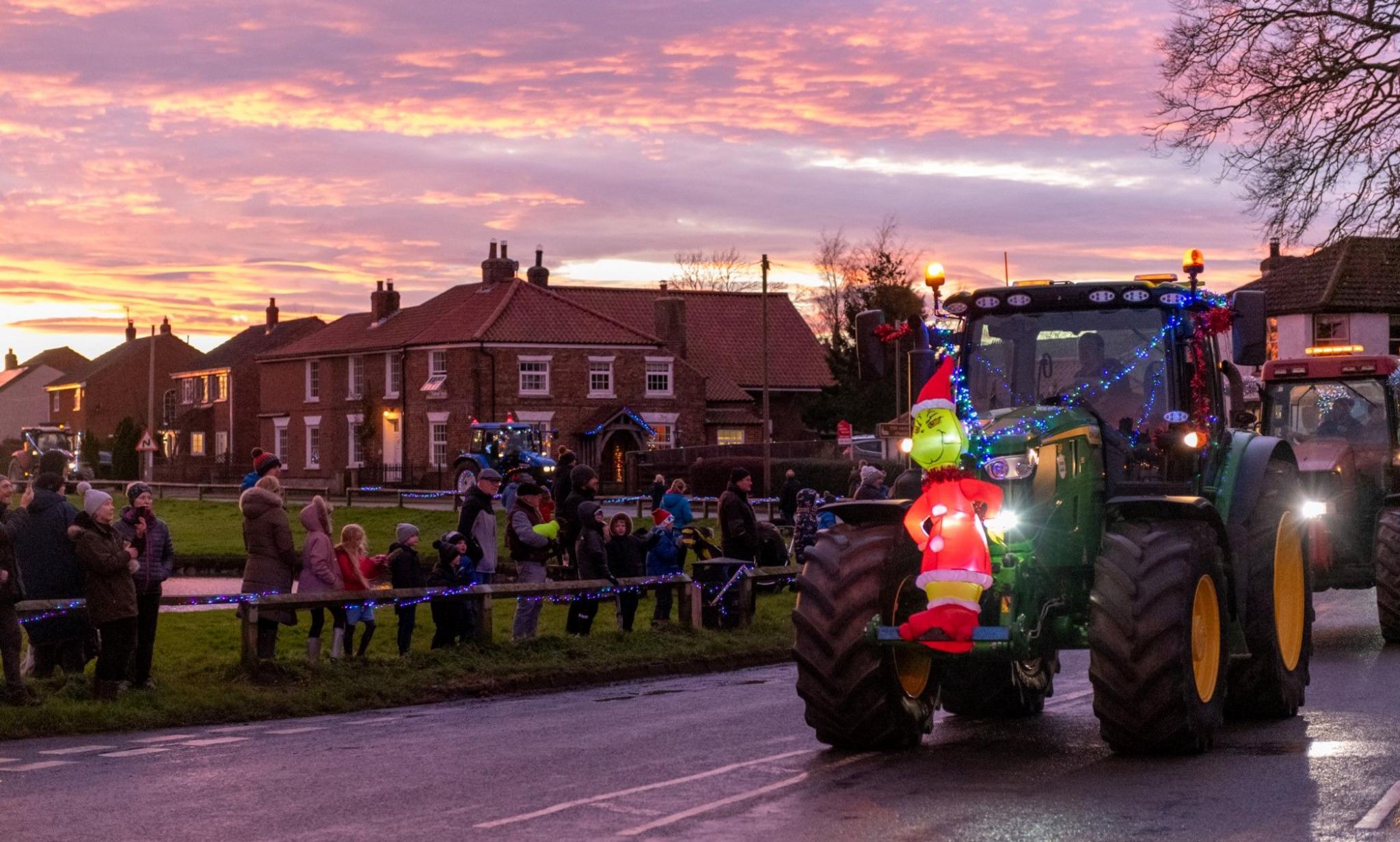 A tractor with an inflatable Grinch character on the front joins the procession. 