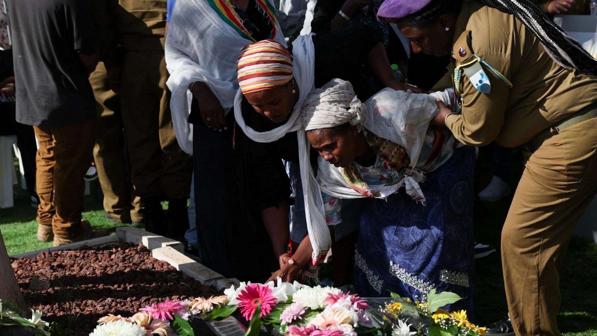 The mother of Israeli soldier Sgt Shahar Manoav is assisted as she mourns over her son's grave, during his funeral in Ashkelon, Israel (25 June 2025)
