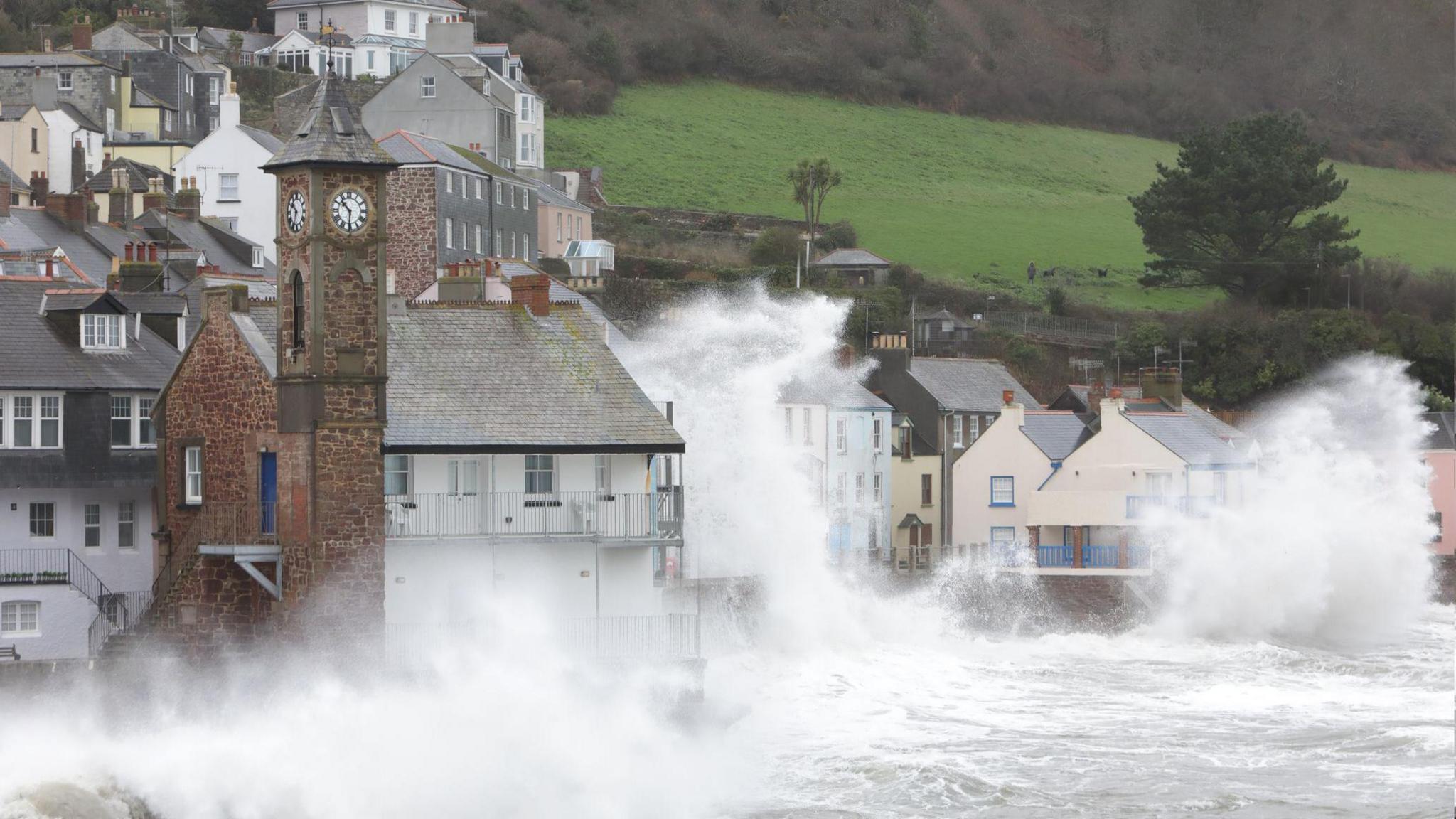 Coastal village during a storm, with waves smashing up on the houses.