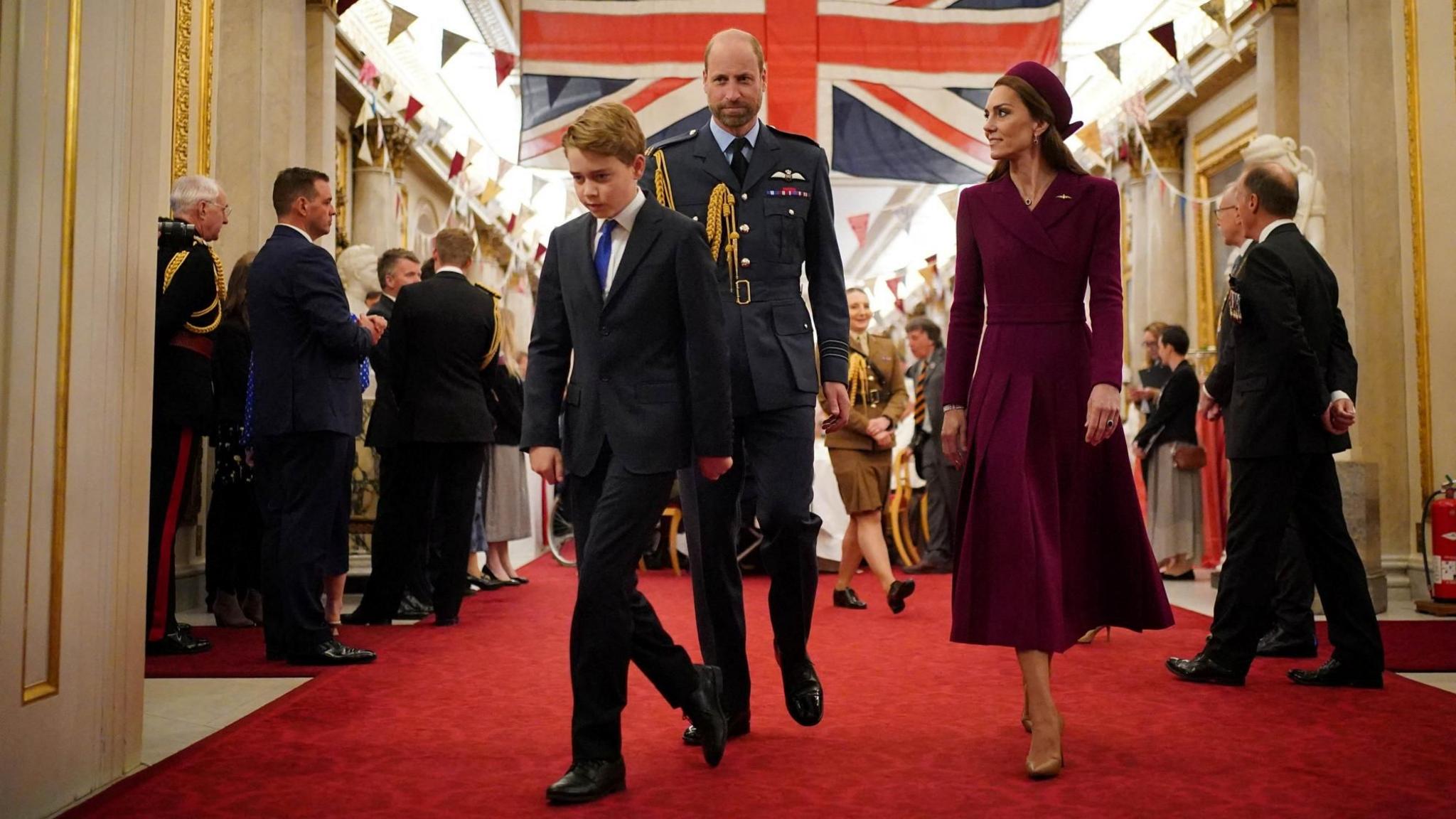 Prince George walks out of a room in Buckingham Palace followed by his mother and father, the Prince and Princess of Wales