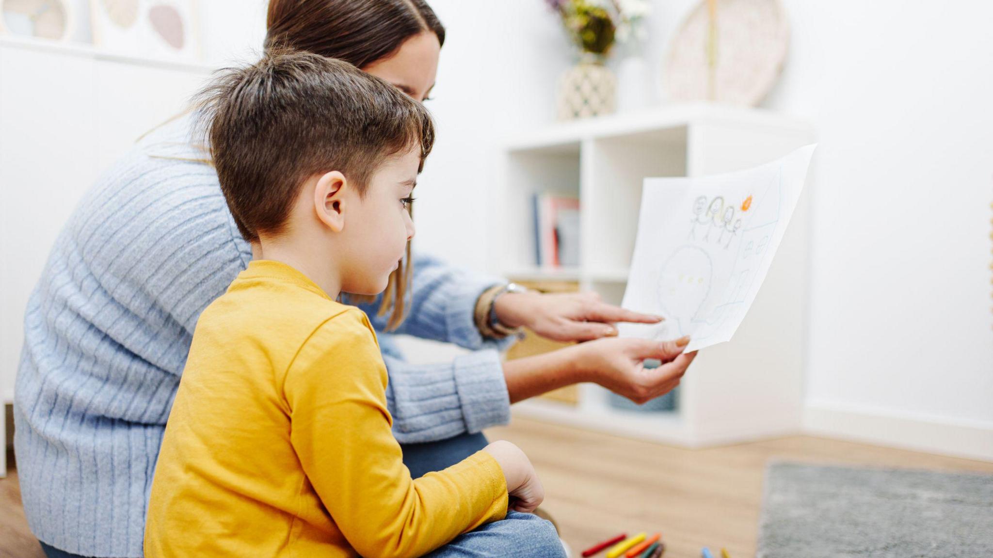 Young woman holding a picture conducting child's psychological test. 