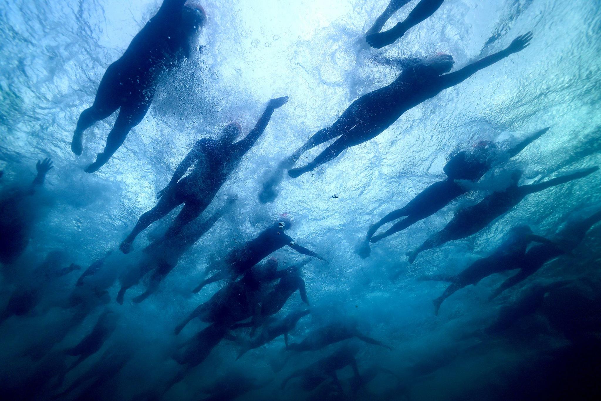 Athletes pass overhead in Lake Taupo as they compete in the swim during an Ironman in Taupo, New Zealand