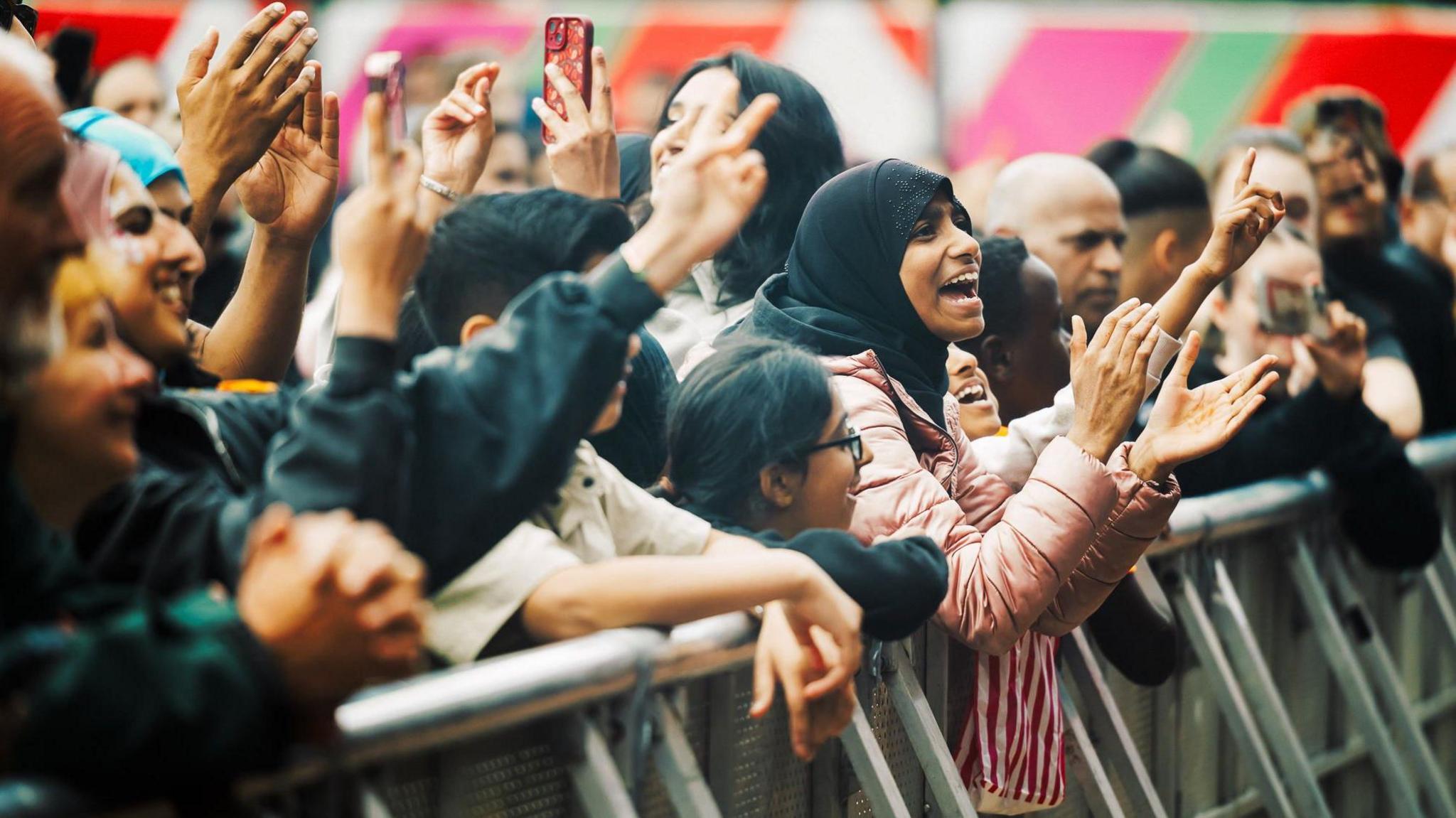 Cheering crowd members at the barrier in front of the stage where acts at the festival perform
