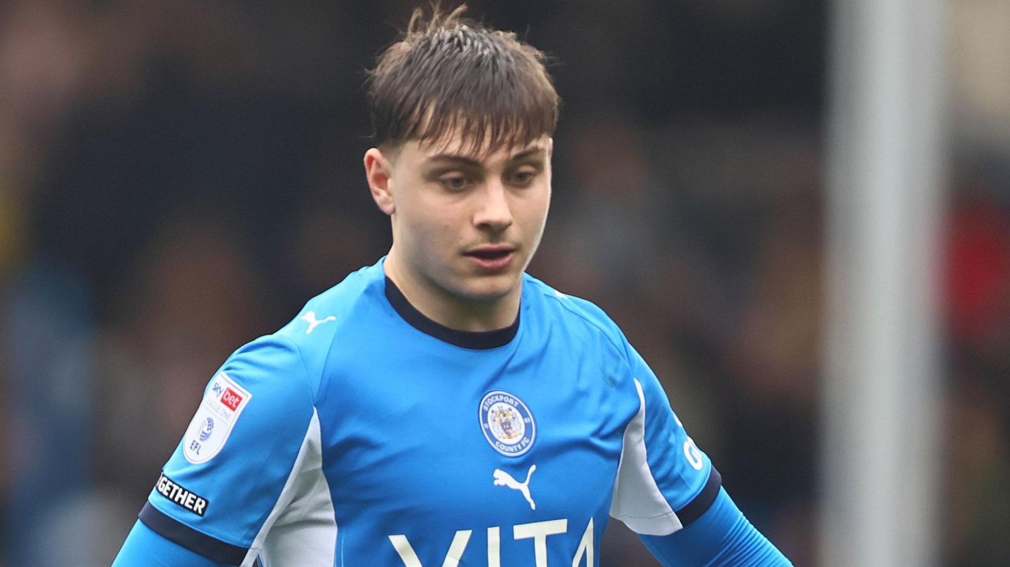 Josh Stokes wearing the blue shirt of Stockport County