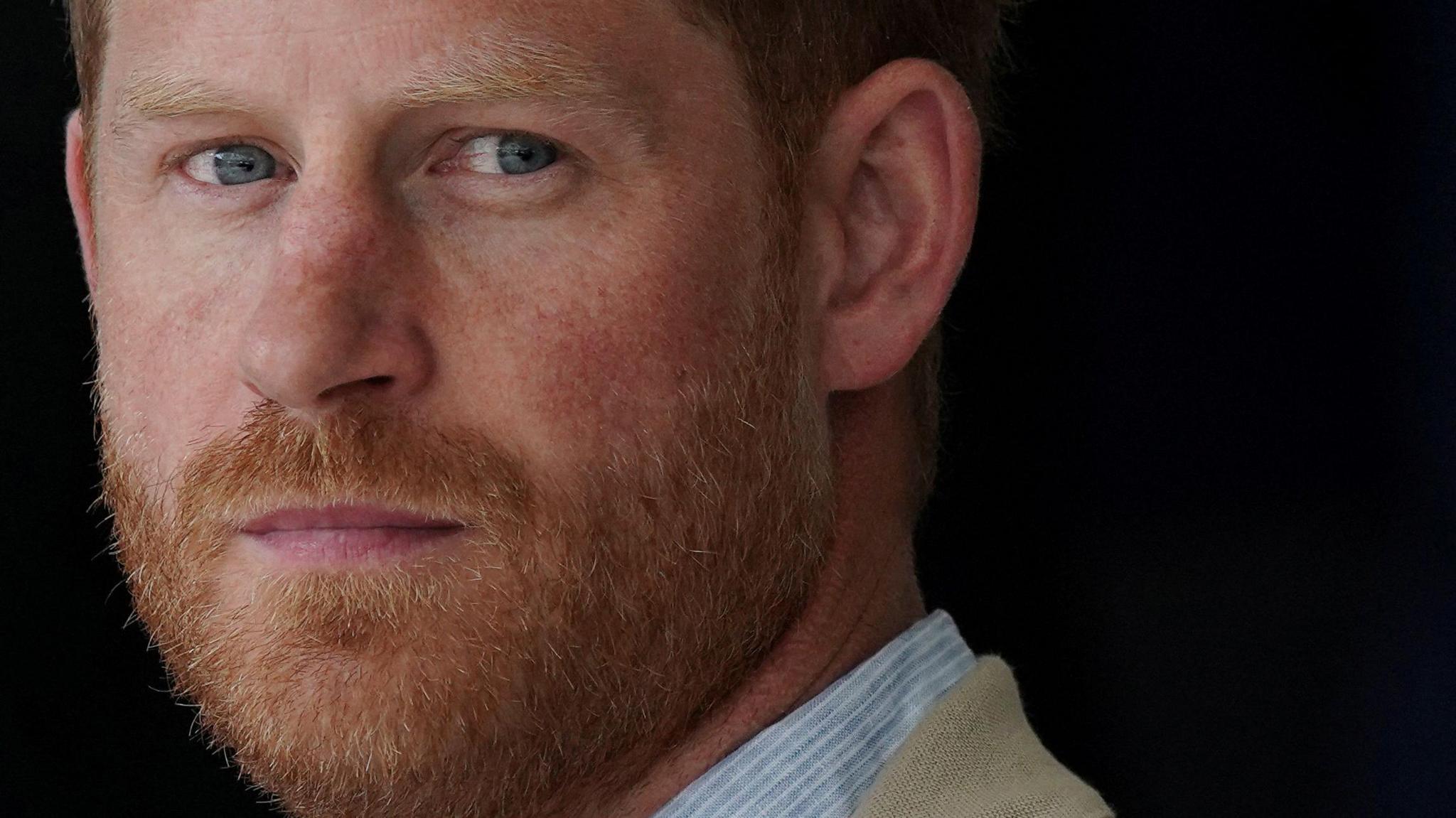 A close-up of Prince Harry, unsmiling, and looking straight at the camera
