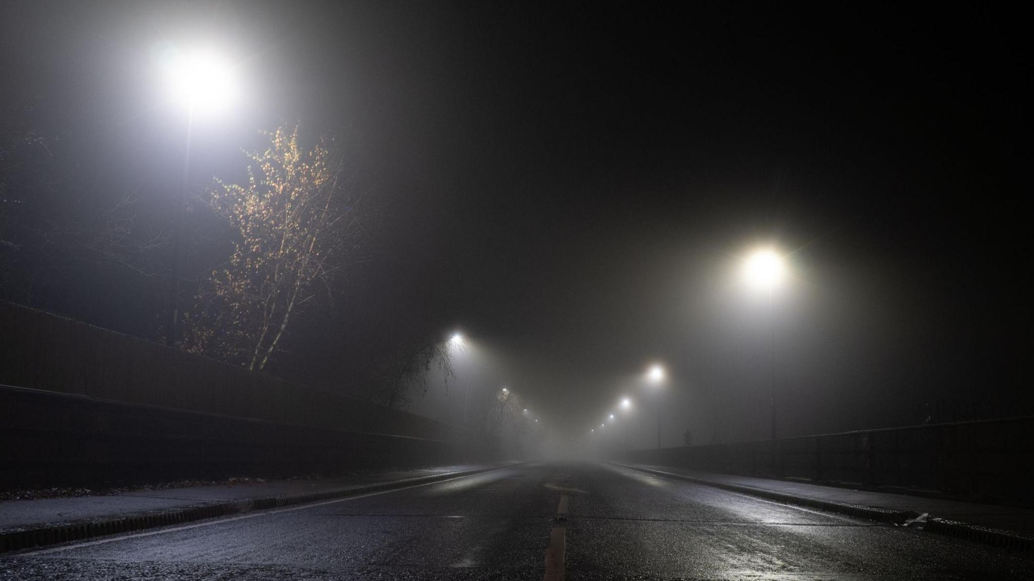 Looking up at a road and street lights on an atmospheric foggy winter's night on a UK road 