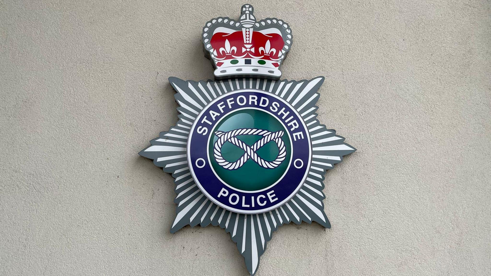 A large crest on a wall, with the words Staffordshire Police around the edge, and an image of a knot in the middle