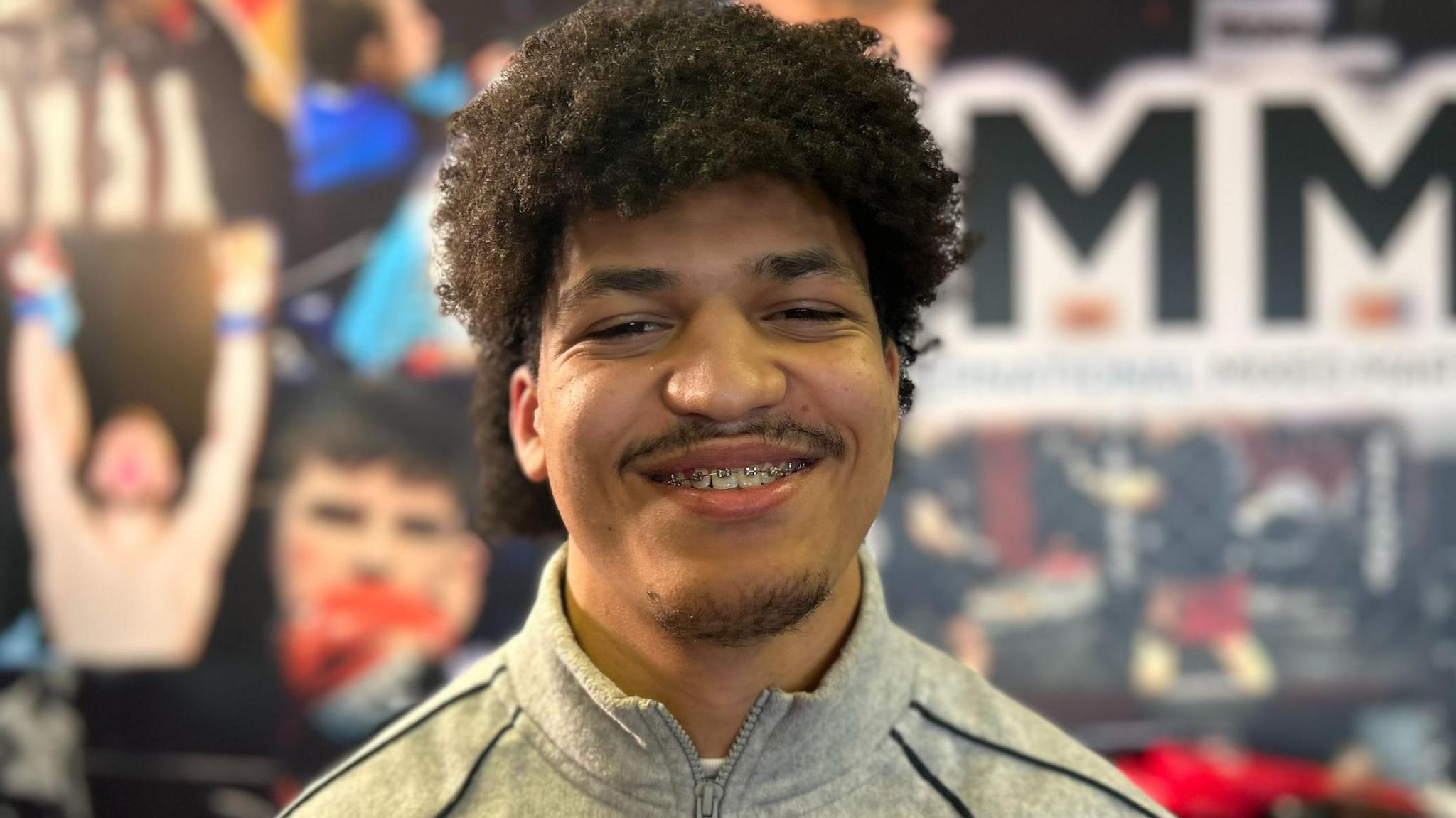 Leonardo Mereles has curly brown hair and braces. He is smiling at the camera, wearing a grey tracksuit top.