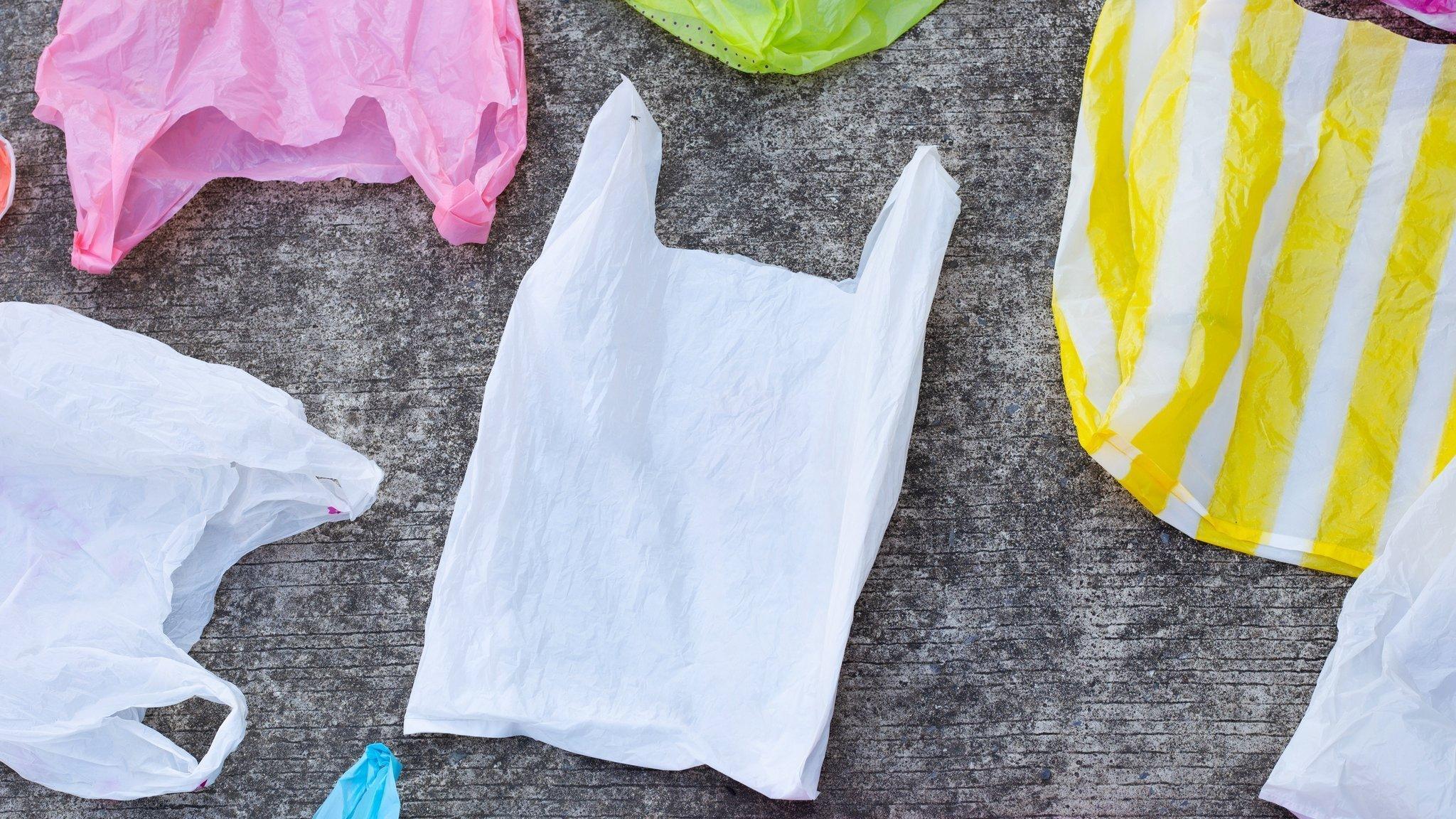 Colourful plastic carrier bags laid out on concrete ground