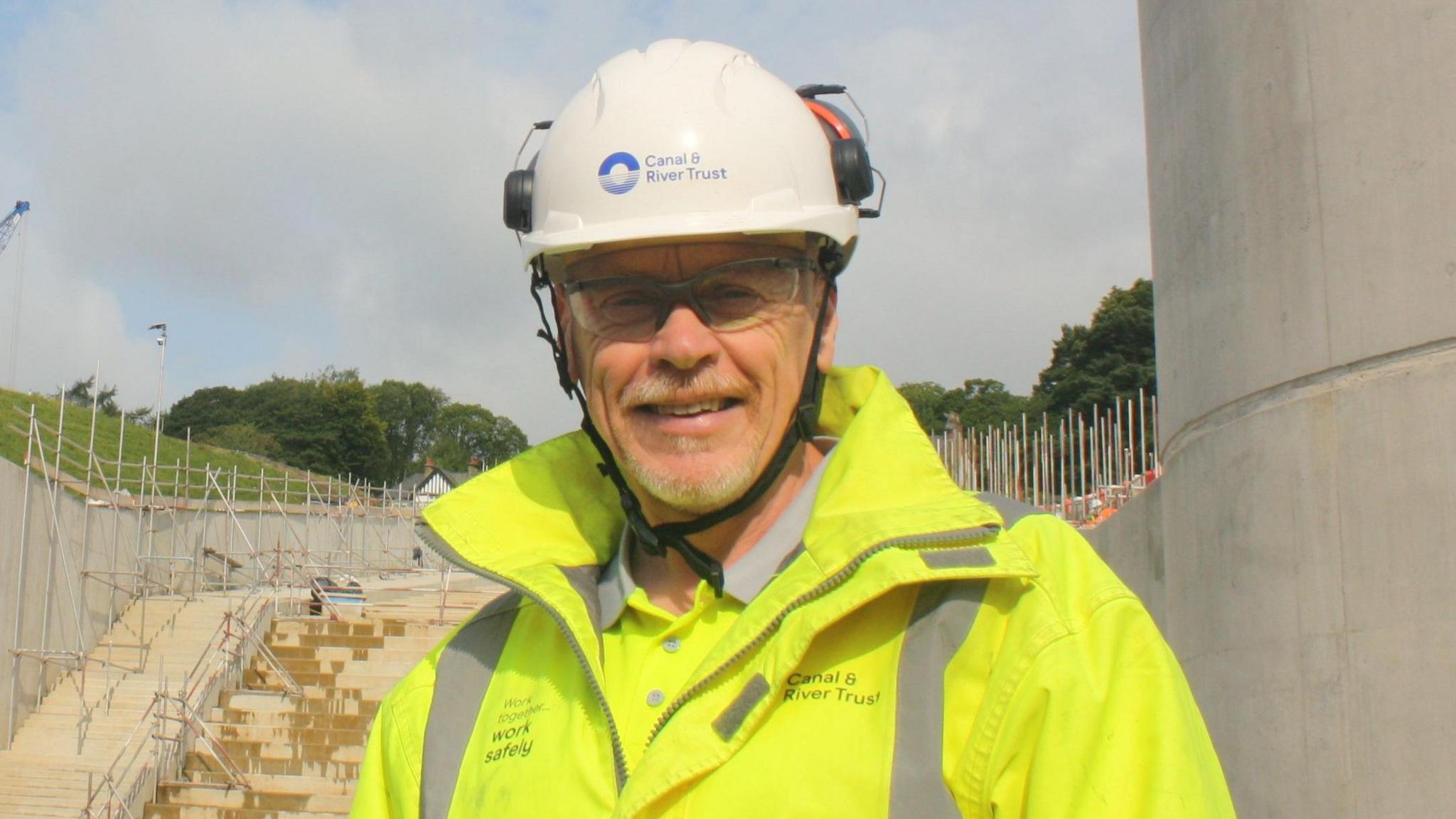 Dilwyn Parry, who is Toddbrook project manager for the Canal and River Trust, is pictured on the construction site wearing a branded white hard hat and yellow fluorescent jacket