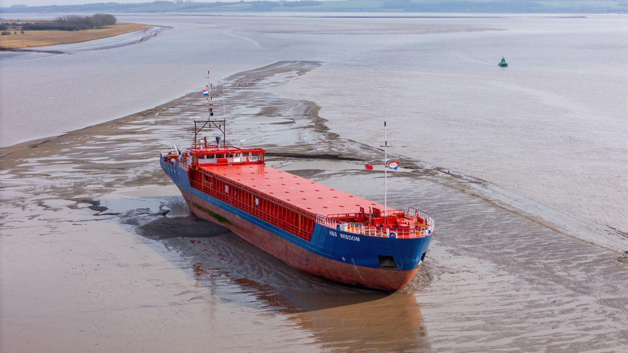 A red and blue cargo ship stuck in mud on the Humber. The photo is taken from an aerial perspective.