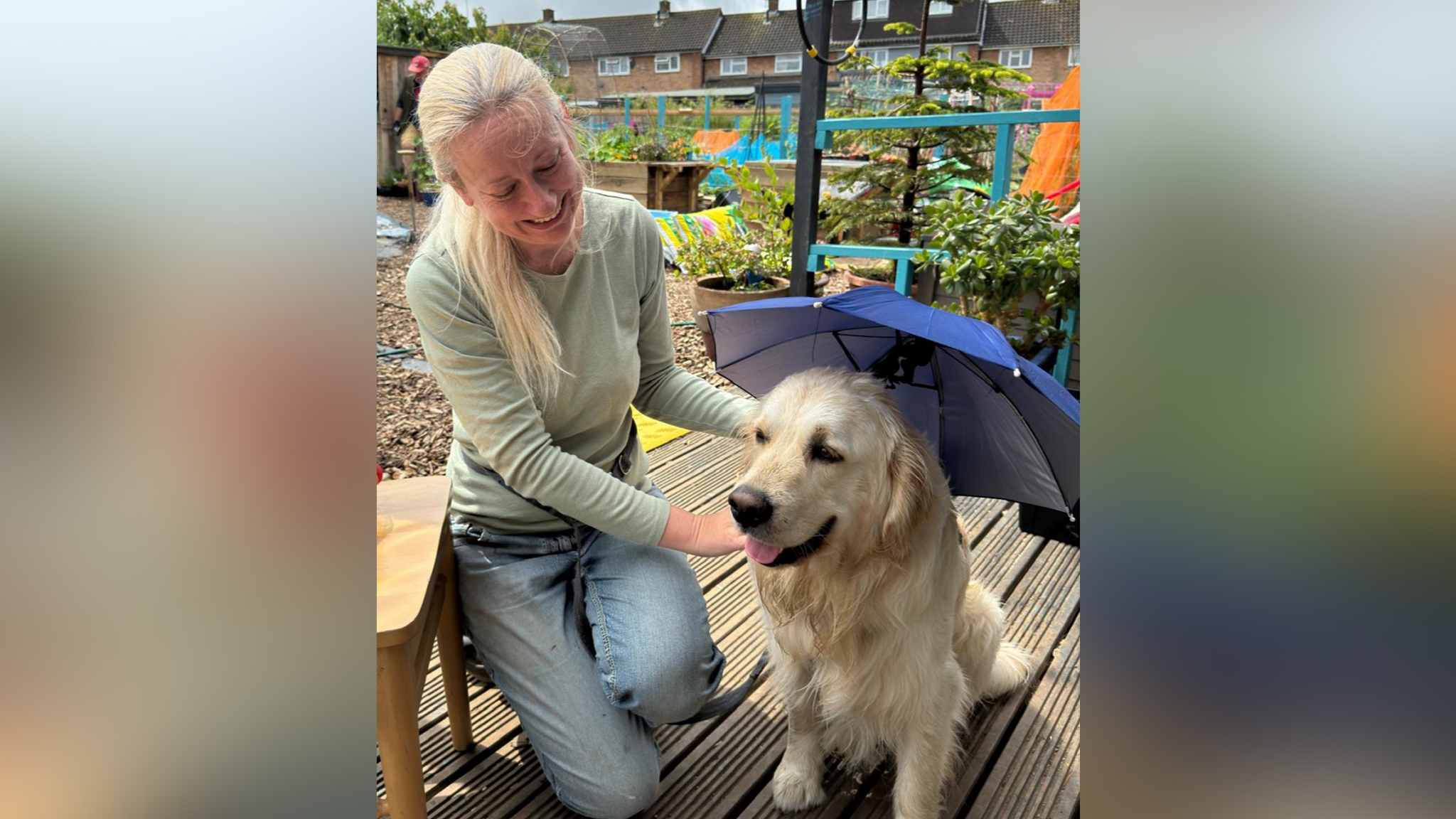 Rowen Saunders knelt on decking and smiling as she holds Pickles' collar