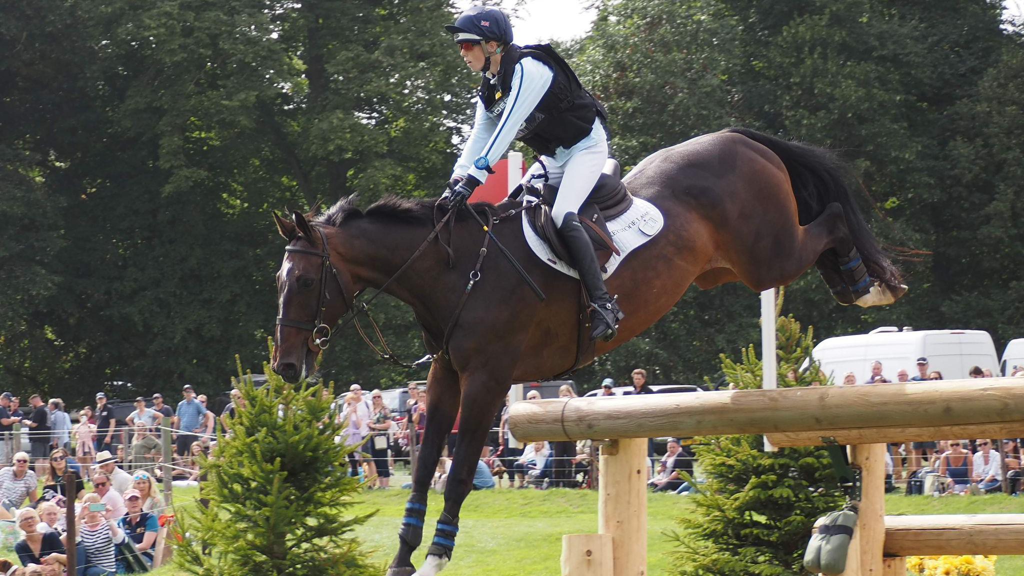 Alice Casburn makes a jump as part of a cross country course, riding by an onlooking crowd at the Burghley horsse Trials in 202