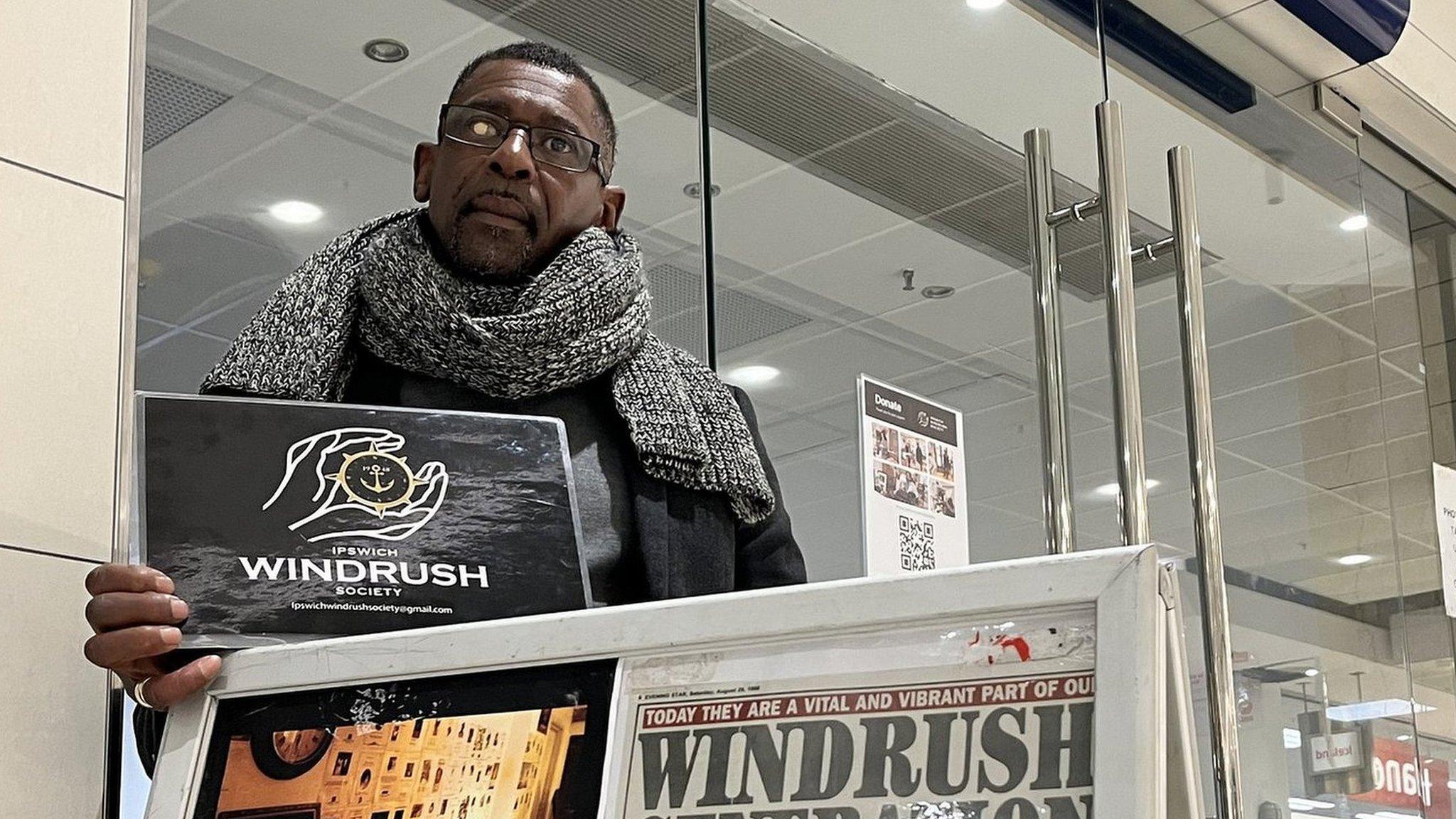 A man outside a shopping unit by an A-board sign