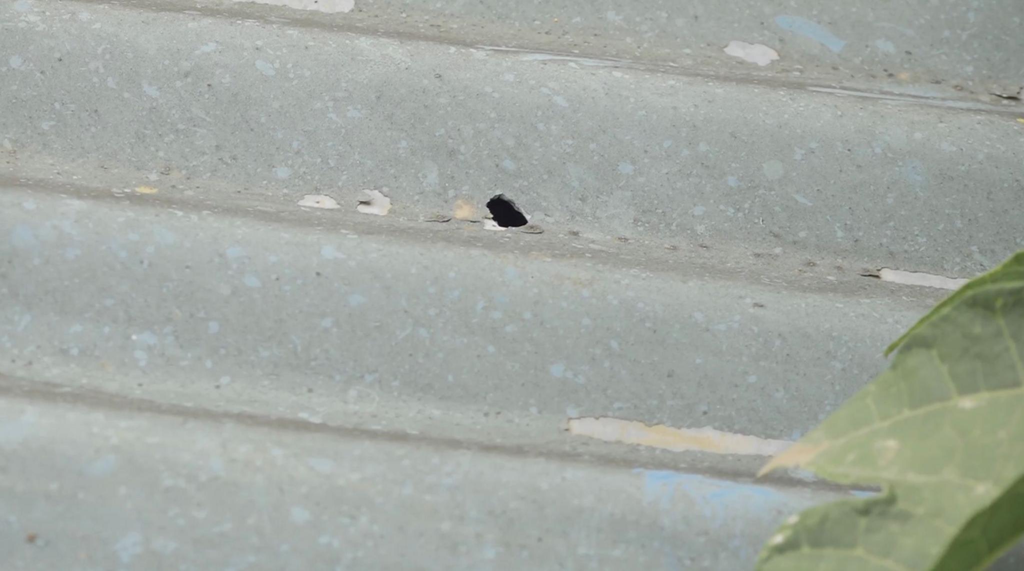 A close-up photo shows a hole in a sheet of iron