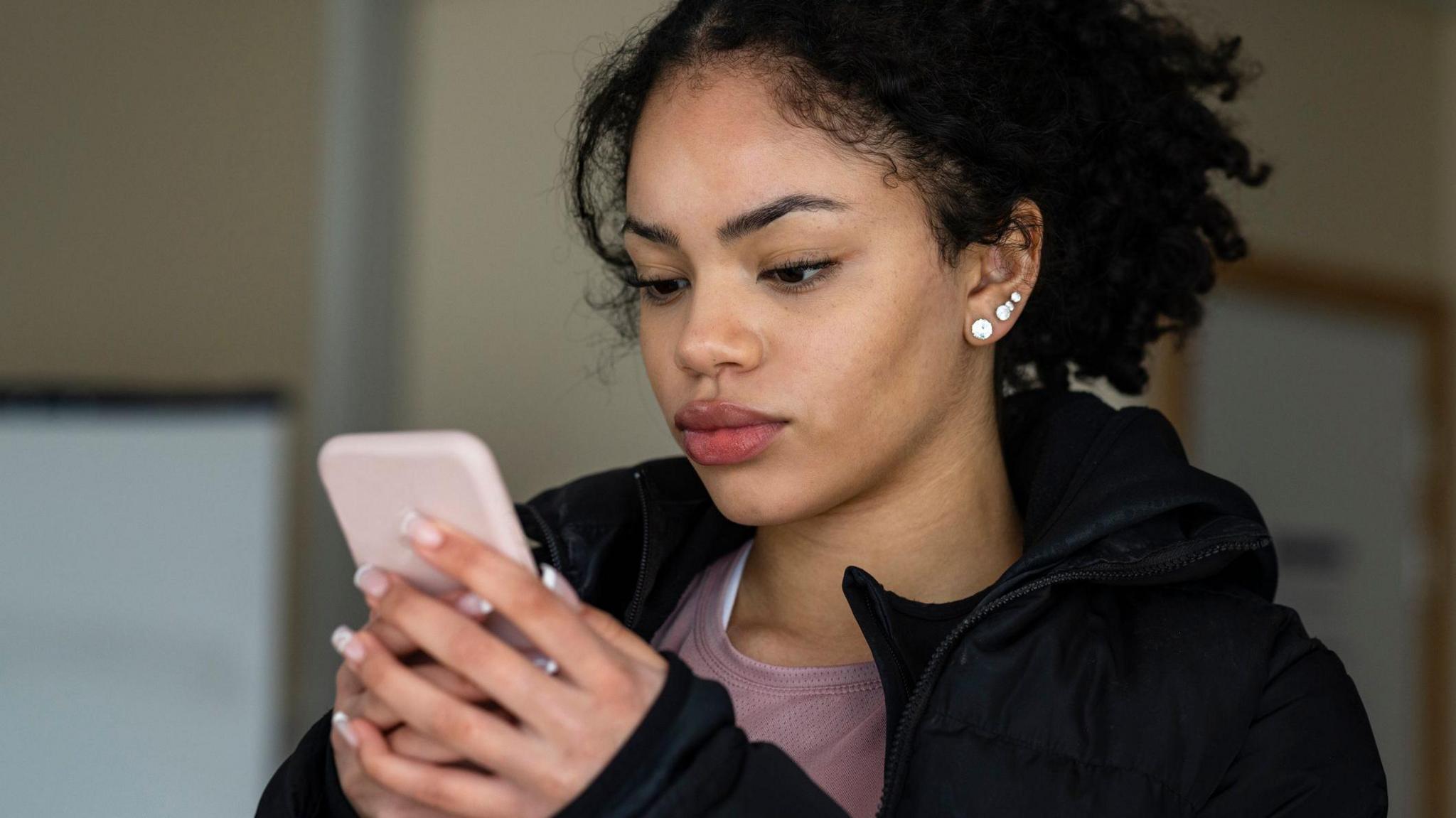 A young woman looks at her phone