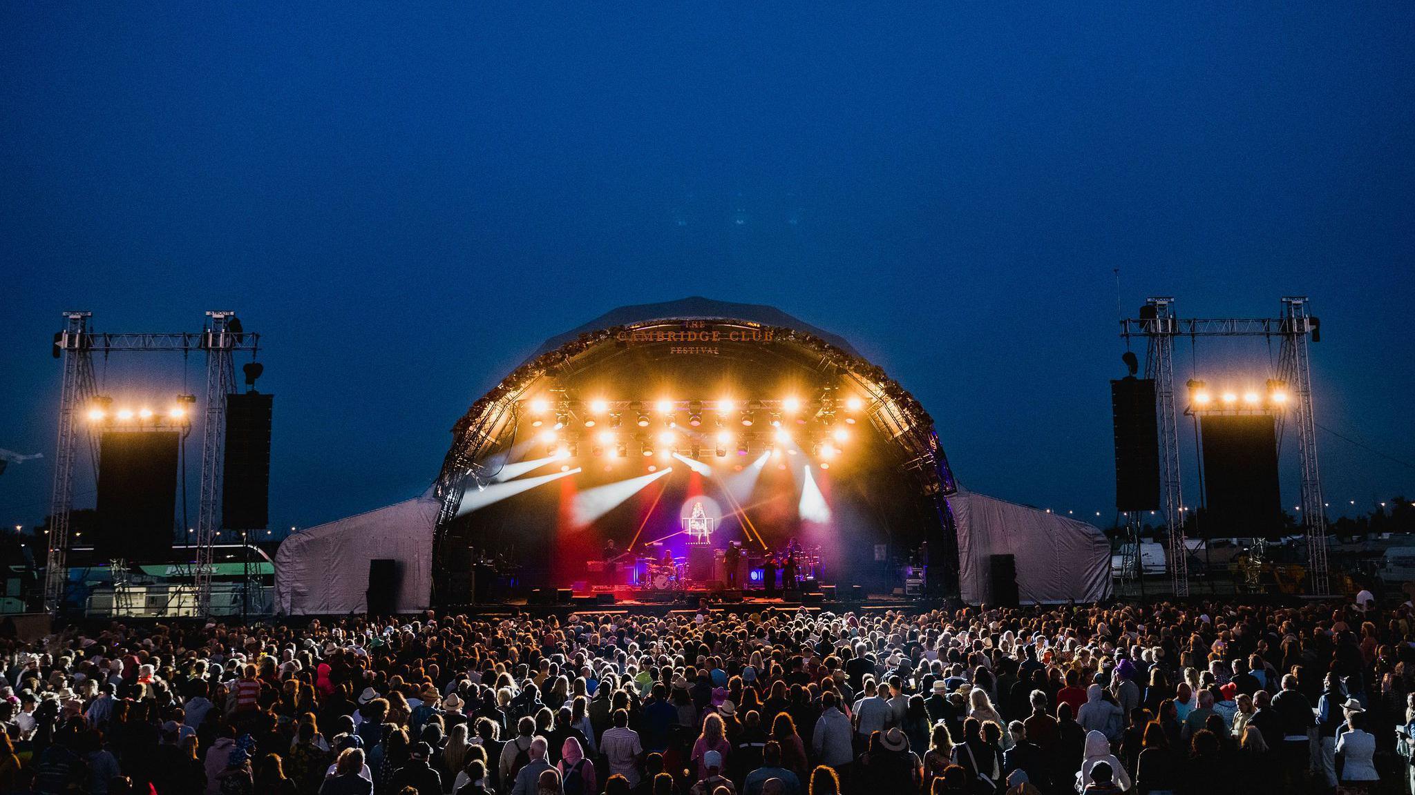 Stage at night lit up with strobe lights and crowd illuminated