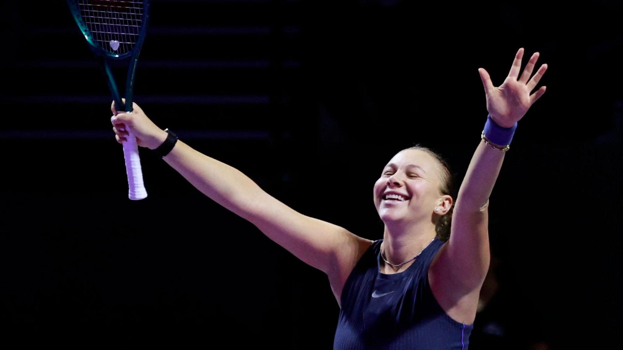 Amanda Anisimova with her hands aloft in celebration
