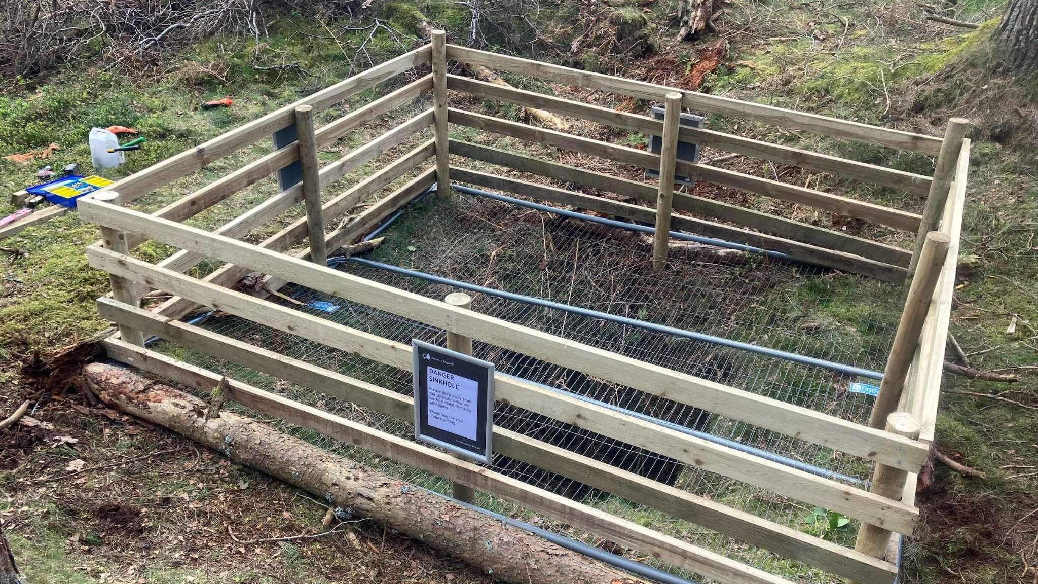 A picture of the sinkhole with fencing around it and a cap on top 