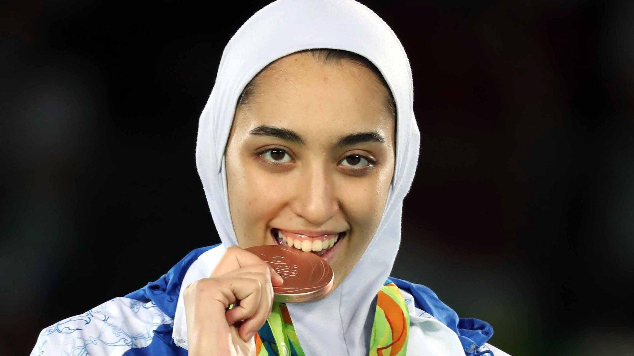 Kimia Alizadeh of Iran celebrates with the national flag after winning the women's -57kg bronze medal bout of the Rio 2016 Olympic Games Taekwondo event