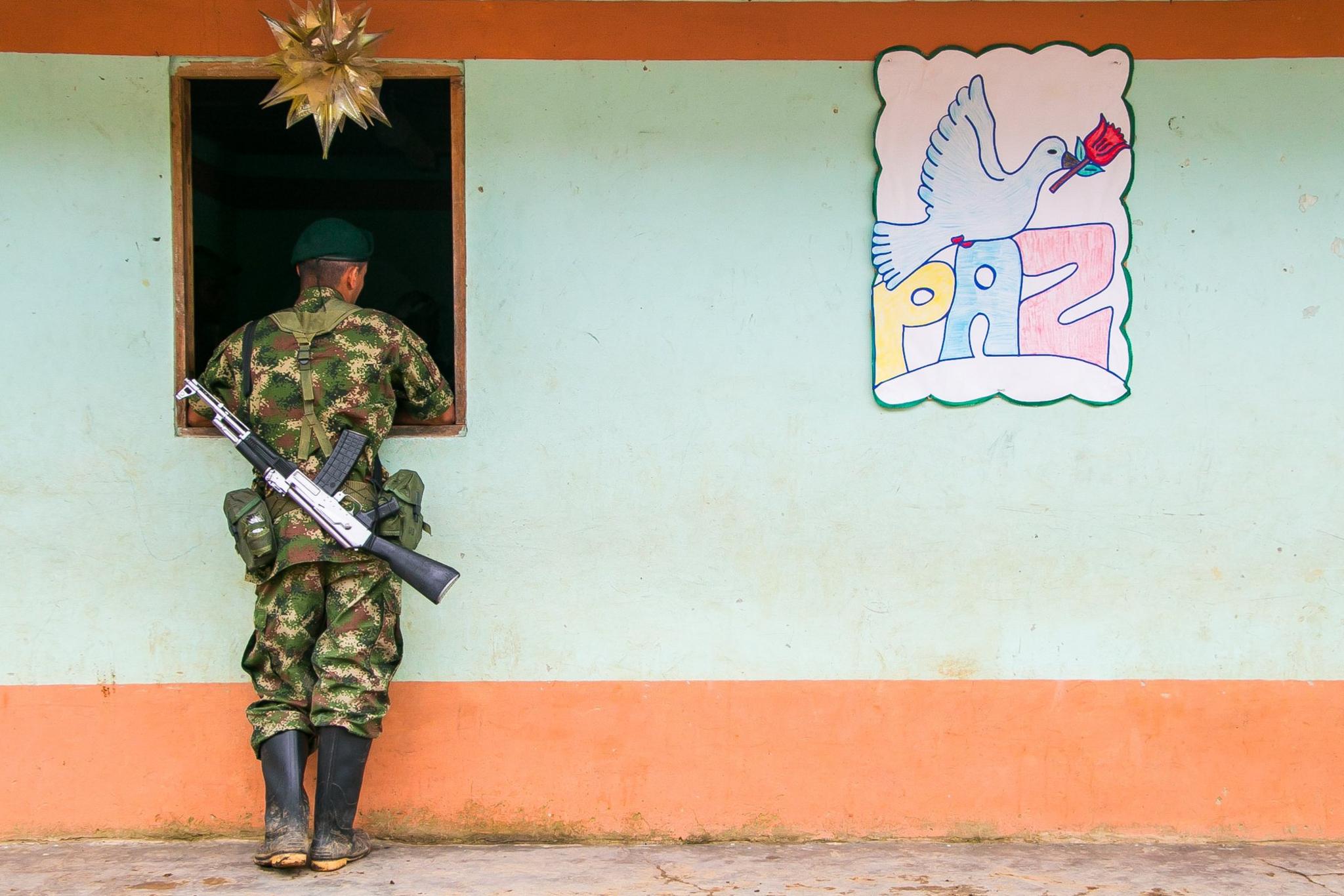 A Farc guerrilla fighter peers through a store window in Santa Lucia, July 2016