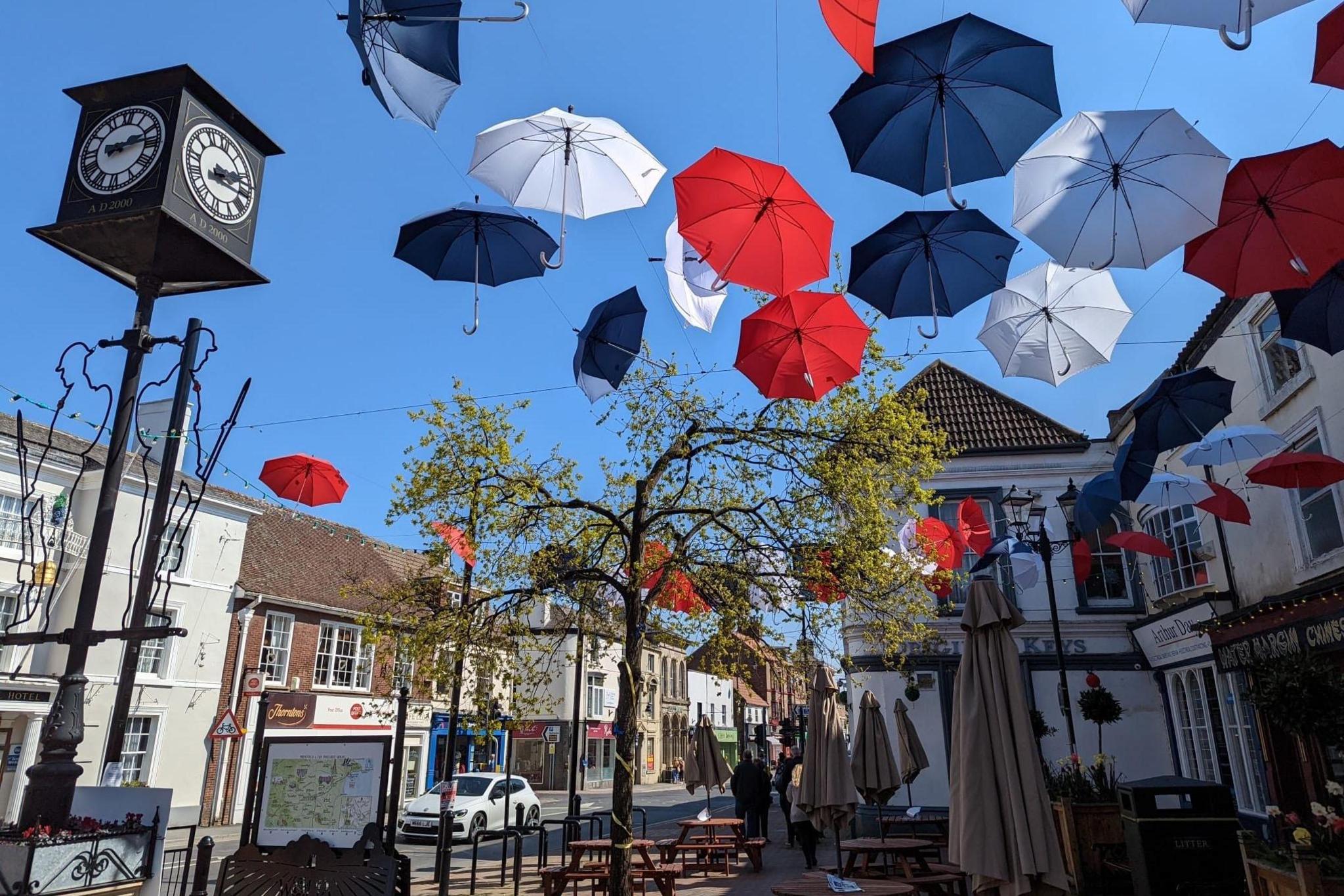 Driffield town centre on a sunny day, there are red, white and blue umbrellas installed outside the Market Place square. 