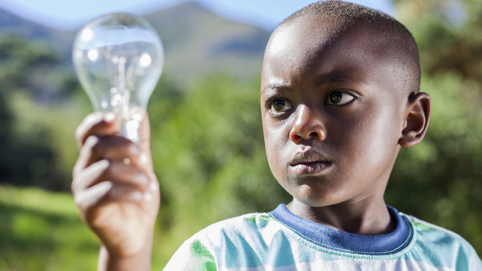 A young boy in Africa holding a light bulb