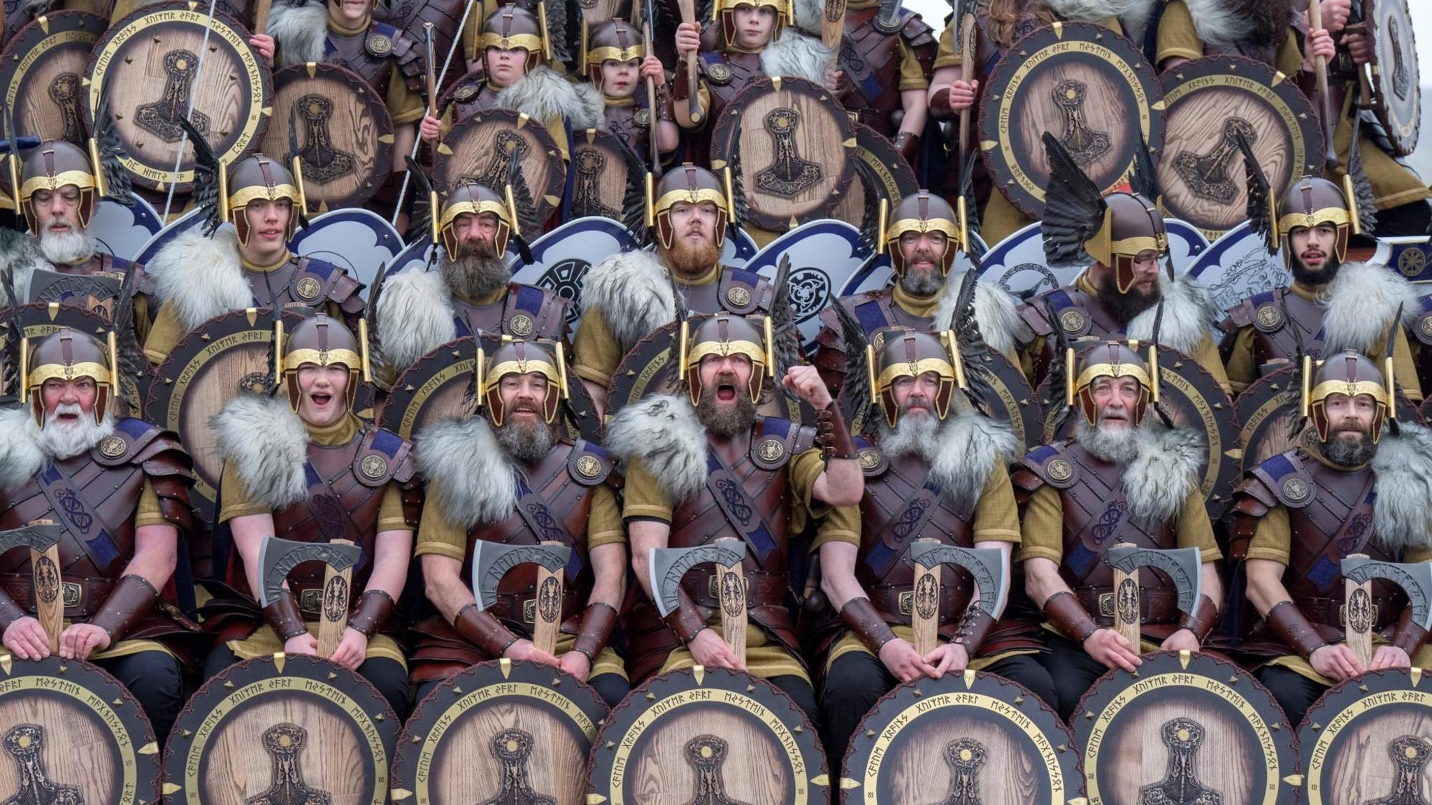 About 25 members of the Jarl Squad in Viking dress with helmets and shields.