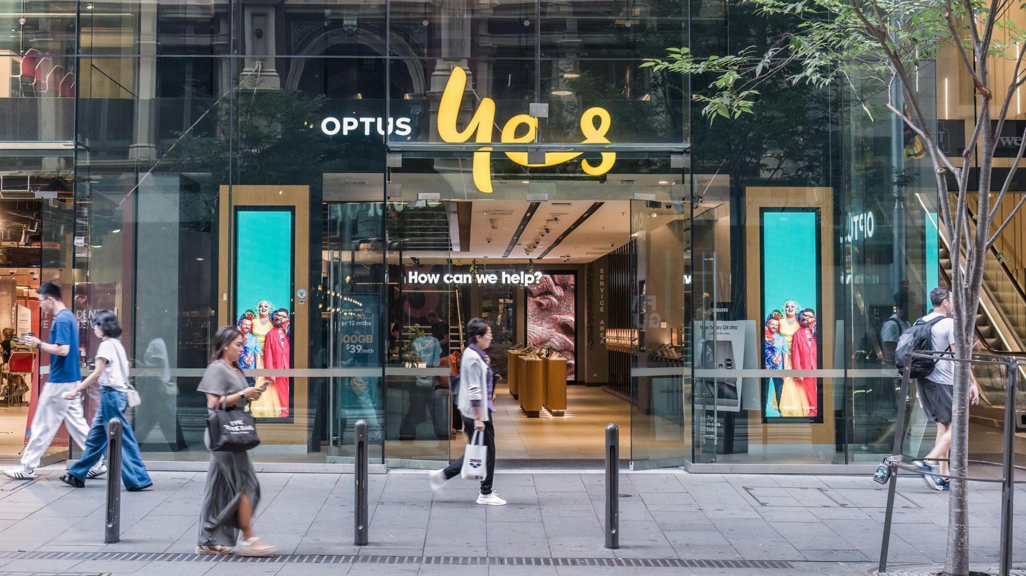 People walk past an Optus storefront