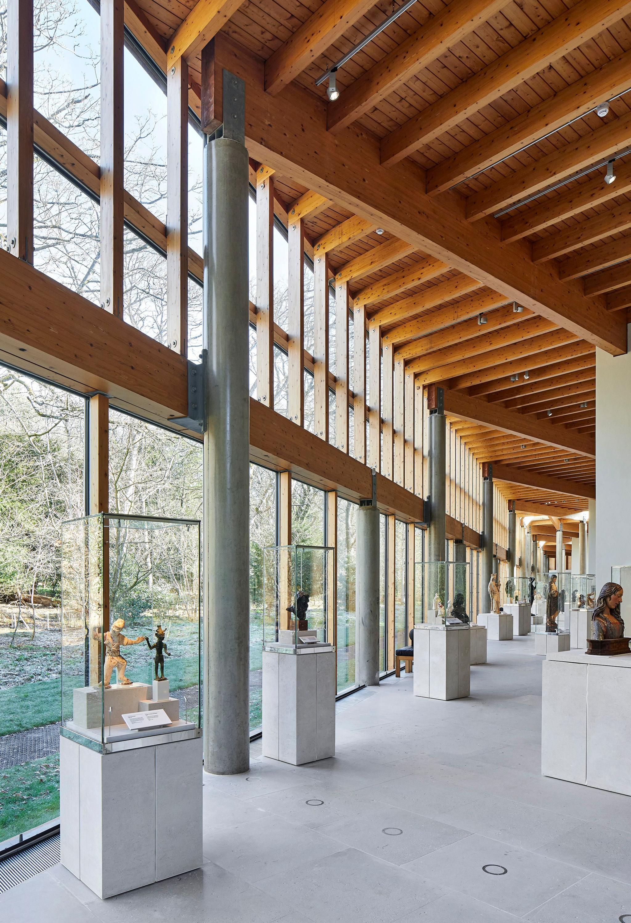 A row of display cases containing artefacts lines the gallery with light flooding in from the wall of windows