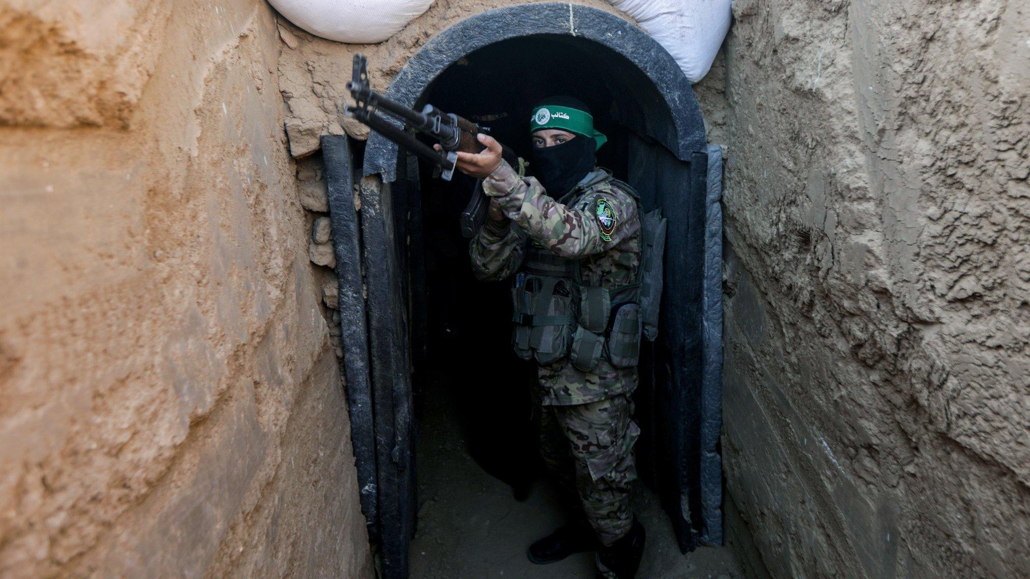 A fighter from Hamas's military wing, the Izzedine al-Qassam Brigades, stands in front of a tunnel in the Maghazi camp, in central Gaza (19 Jul 2023)