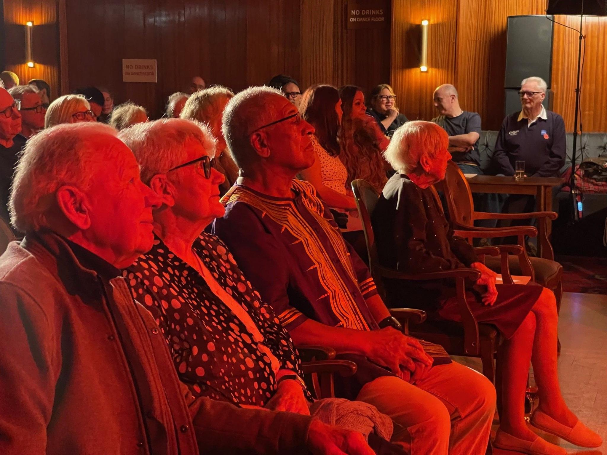 A row of people in seats watching a screening at a social club