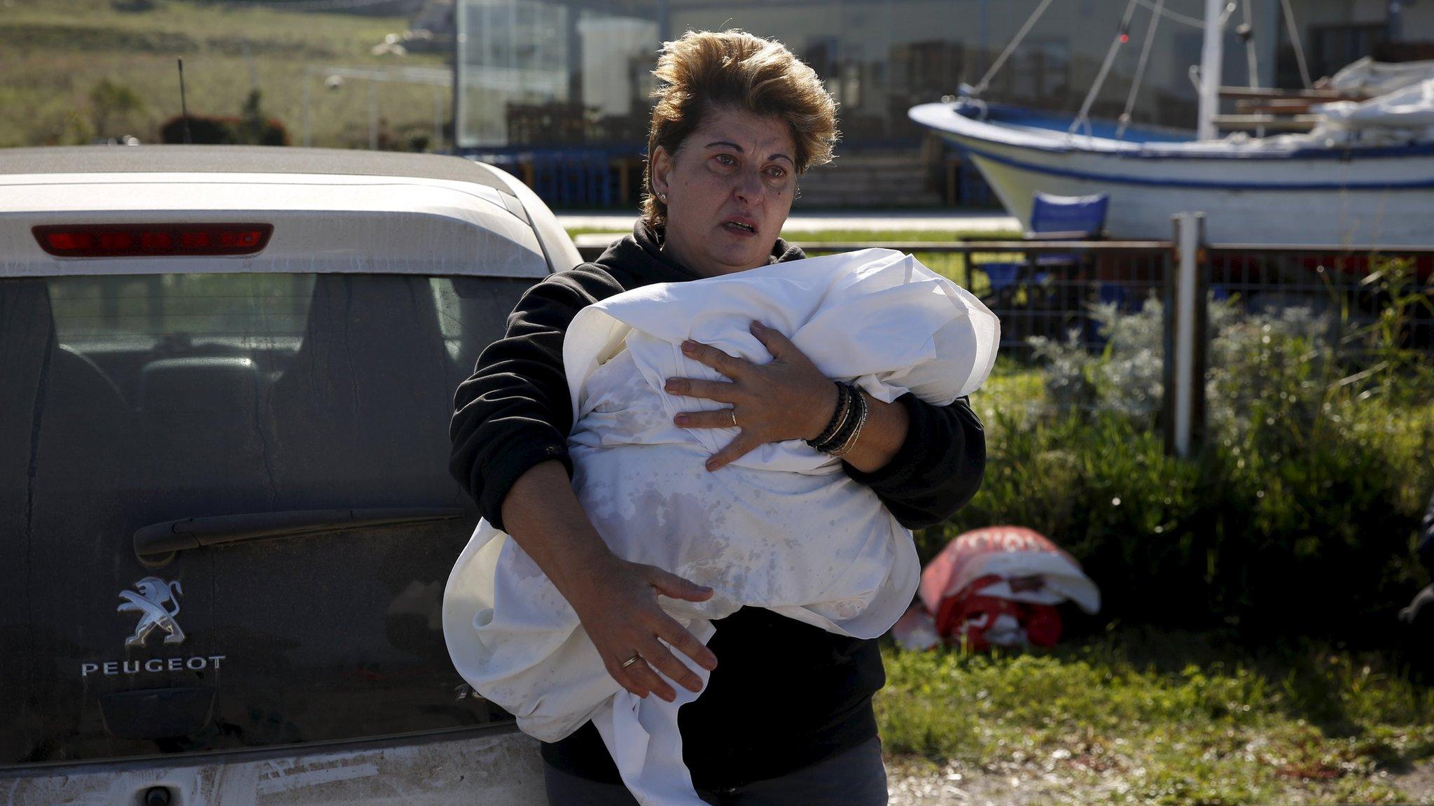 A woman holds the wrapped body of a migrant baby girl, who was said to have been on board a wooden boat carrying refugees and migrants that sank near Lesbos on 28 October (30 October 2015)