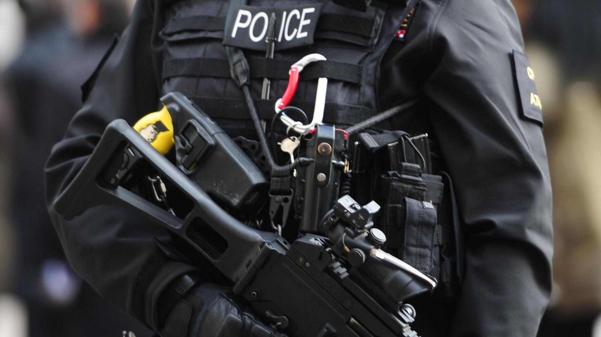 A stock image of an armed police officer holding a machine gun.